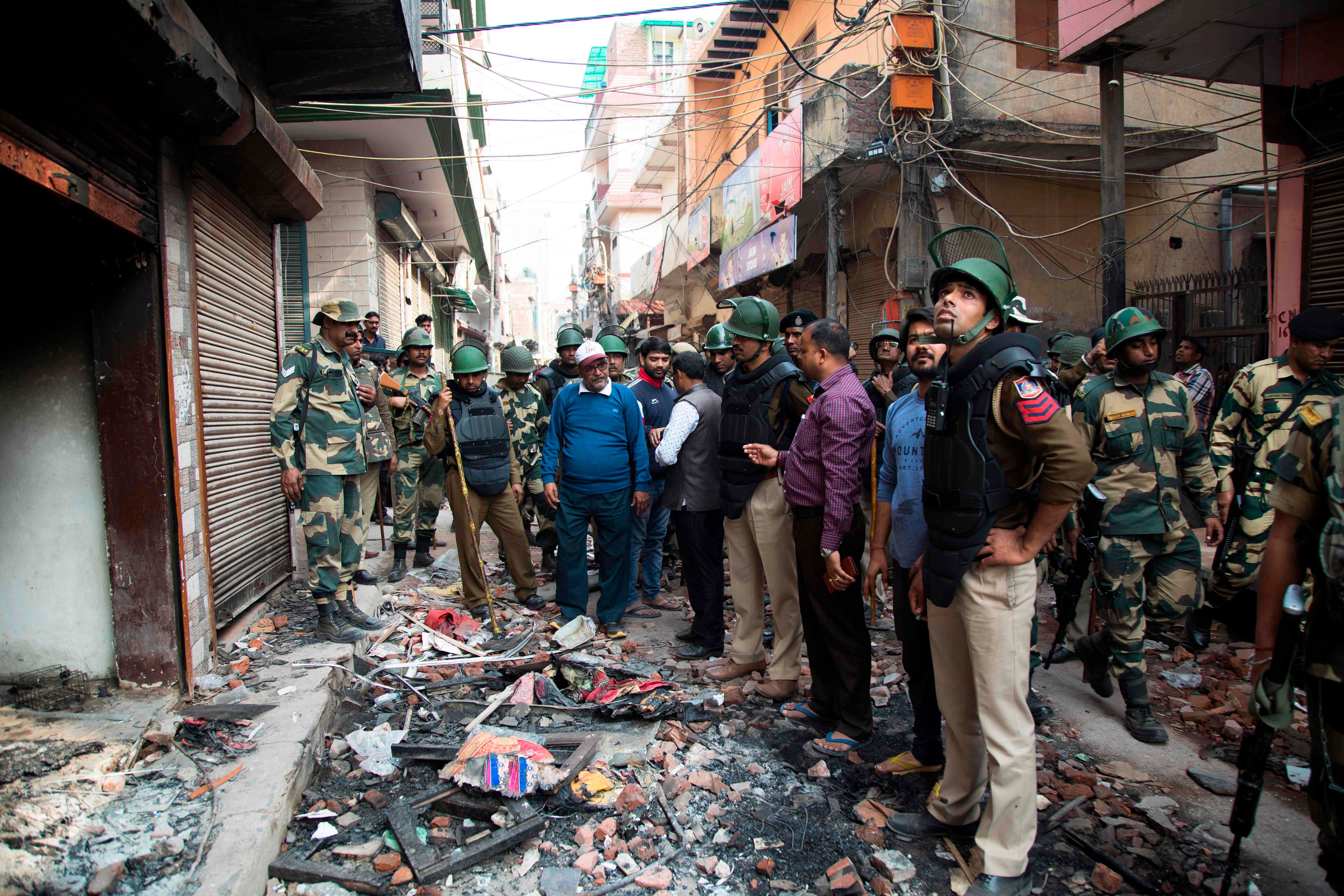 Hindu residents talk to security personnel about material damages done to properties in their neighbourhood following sectarian riots over India's new citizenship law, at Shiv Vihar area in New Delhi. (AFP Photo)