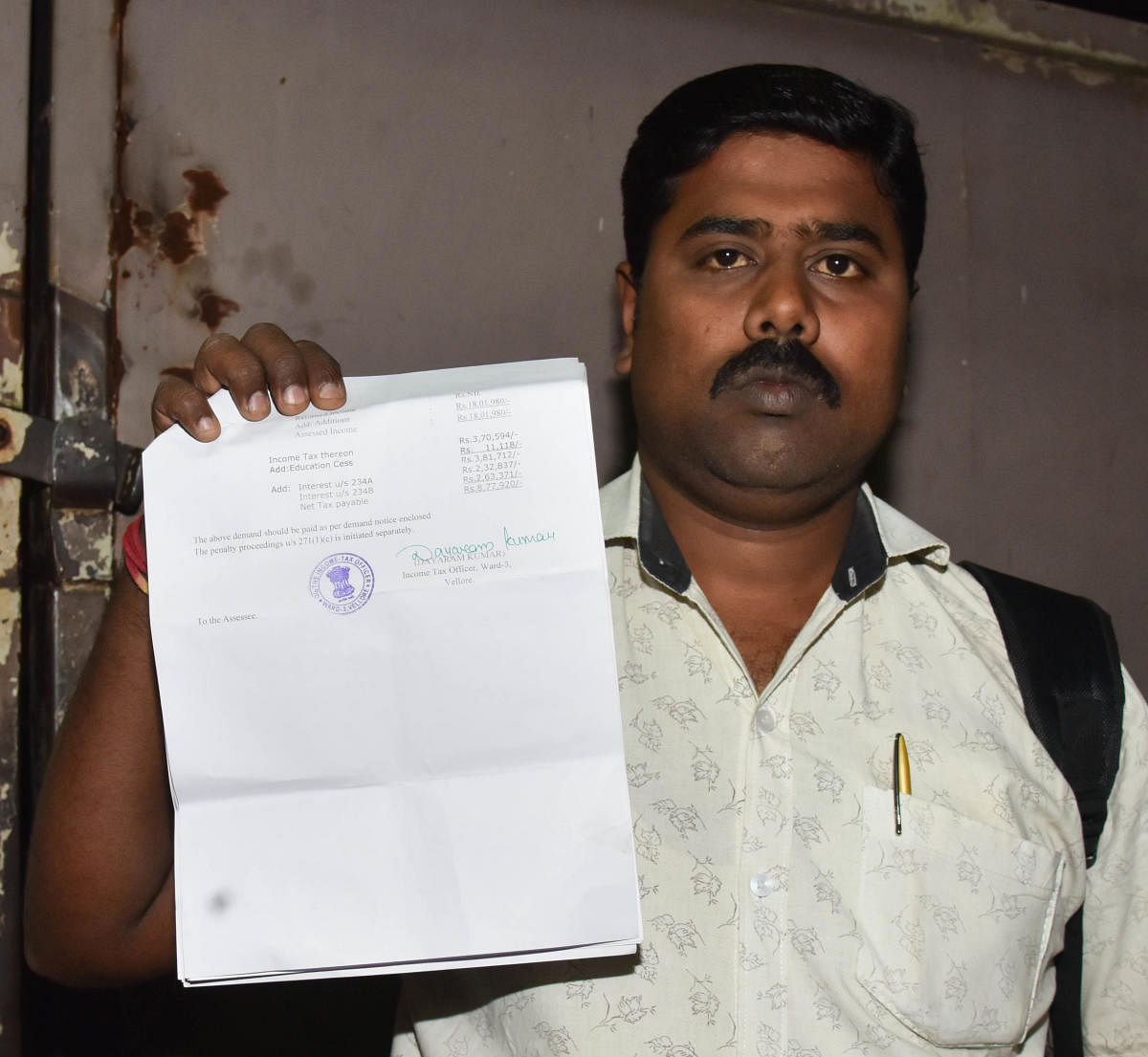 Ramesh Chandramani with the Income Tax notice asking him to pay Rs 8.77 lakh for doing transactions worth Rs 2.25 crore. DH Photo/B H Shivakumar