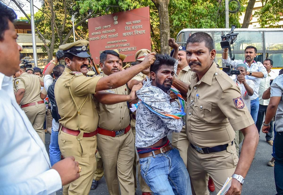 Bengaluru: Policemen detain Congress and Janata Dal (Secular) party workers who tried to deface the signboard of the Income Tax Department during a protest over the I-T raids on supporters of the JD(S) and the Congress, in Bengaluru, Thursday, March 28, 2019. (PTI Photo/Shailendra Bhojak)