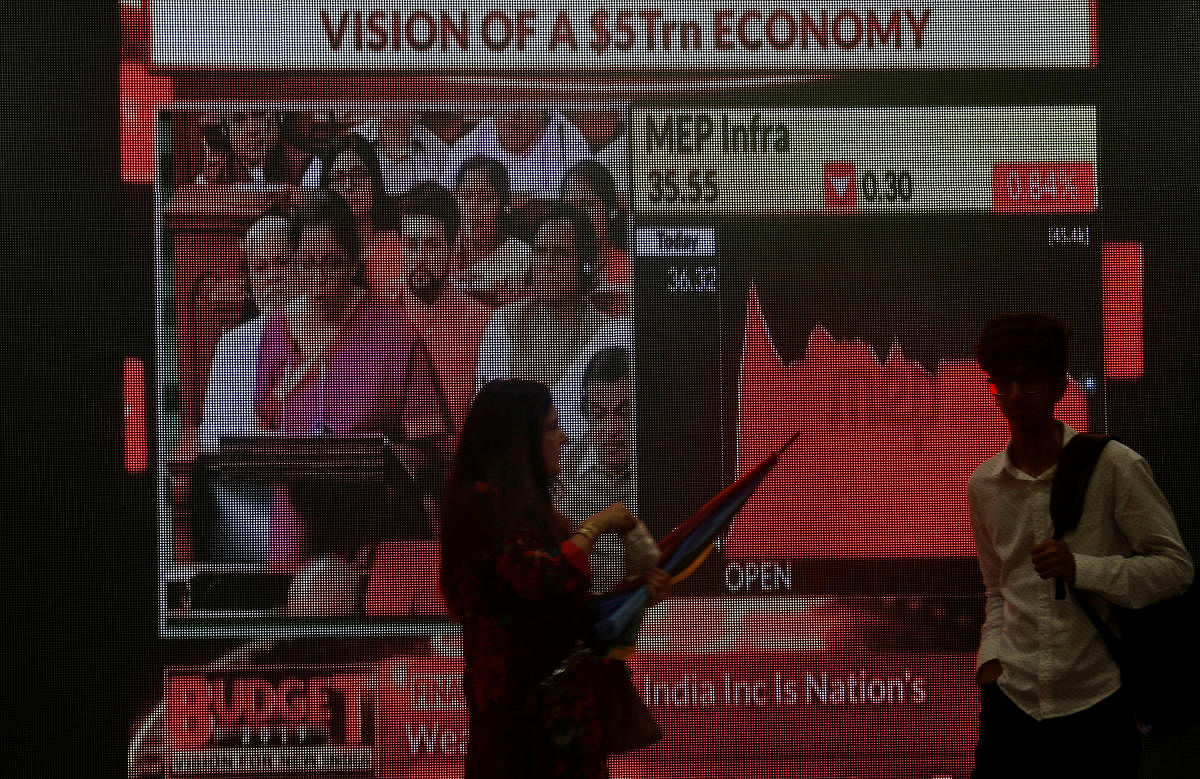 People walk as a telecast of India's Finance Minister Nirmala Sitharaman presenting the budget is displayed inside the Bombay Stock Exchange (BSE) building in Mumbai, India, July 5, 2019. REUTERS