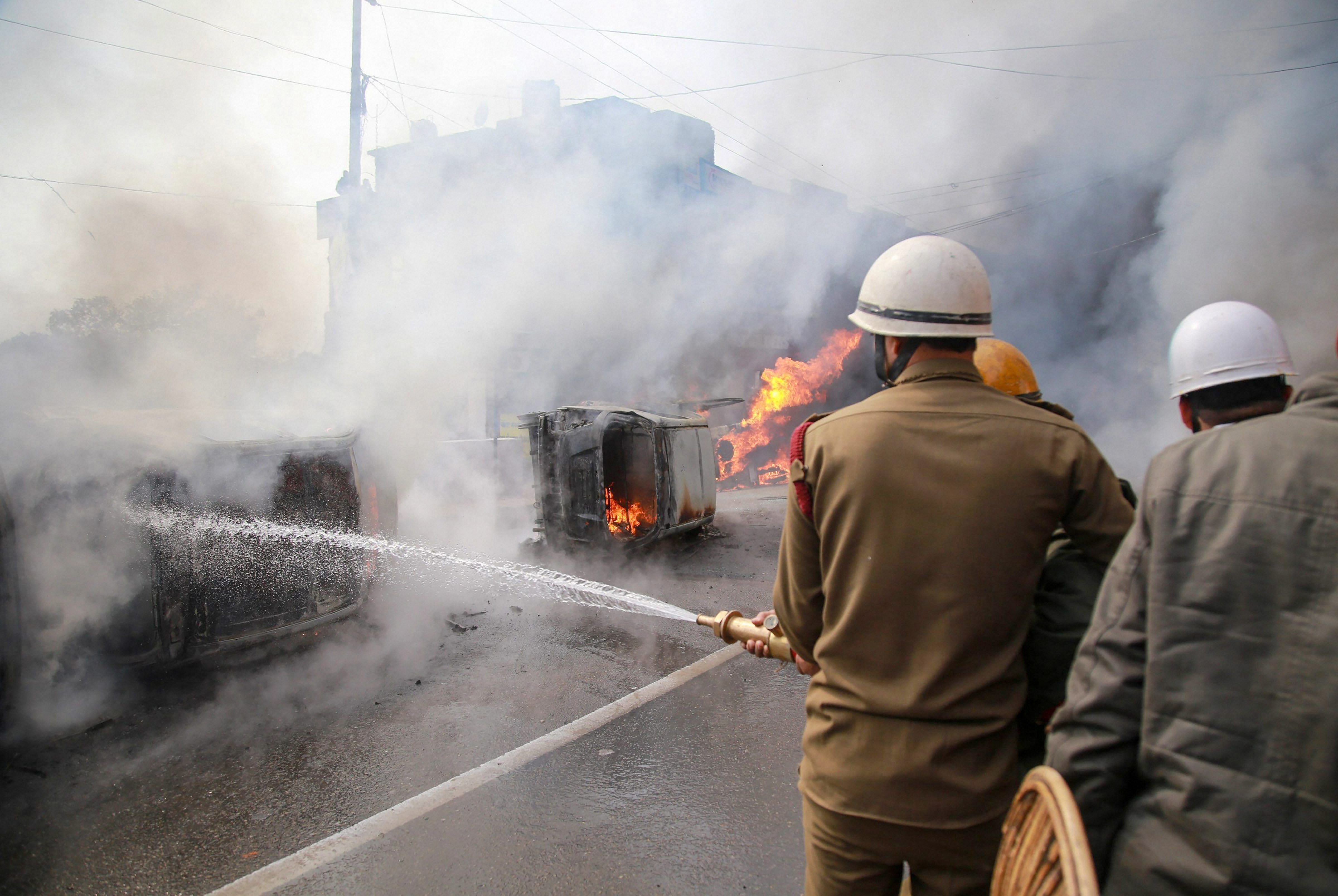 Jammu: Firemen spray water to douse the flames on the vehicles which were set ablaze during a protest against Thursday's Pulwama terror attack, in Jammu, Friday, Feb. 15, 2019. (PTI Photo)