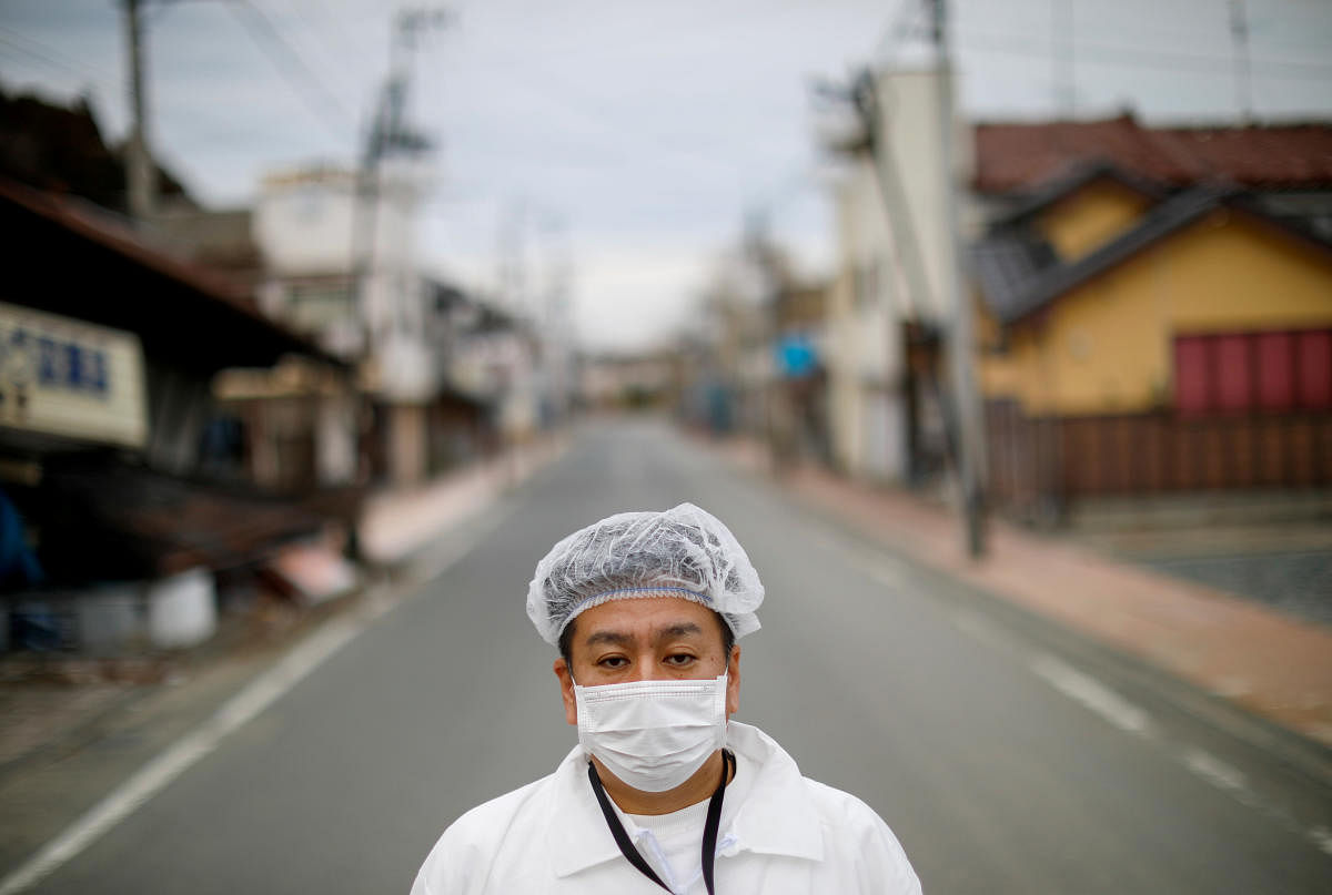 Yuji Onuma, an evacuee from Futaba Town near tsunami-crippled Fukushima Daiichi nuclear power plant, poses for a photograph on the empty street in Fuutaba Town, Fukushima, Japan. Reuters
