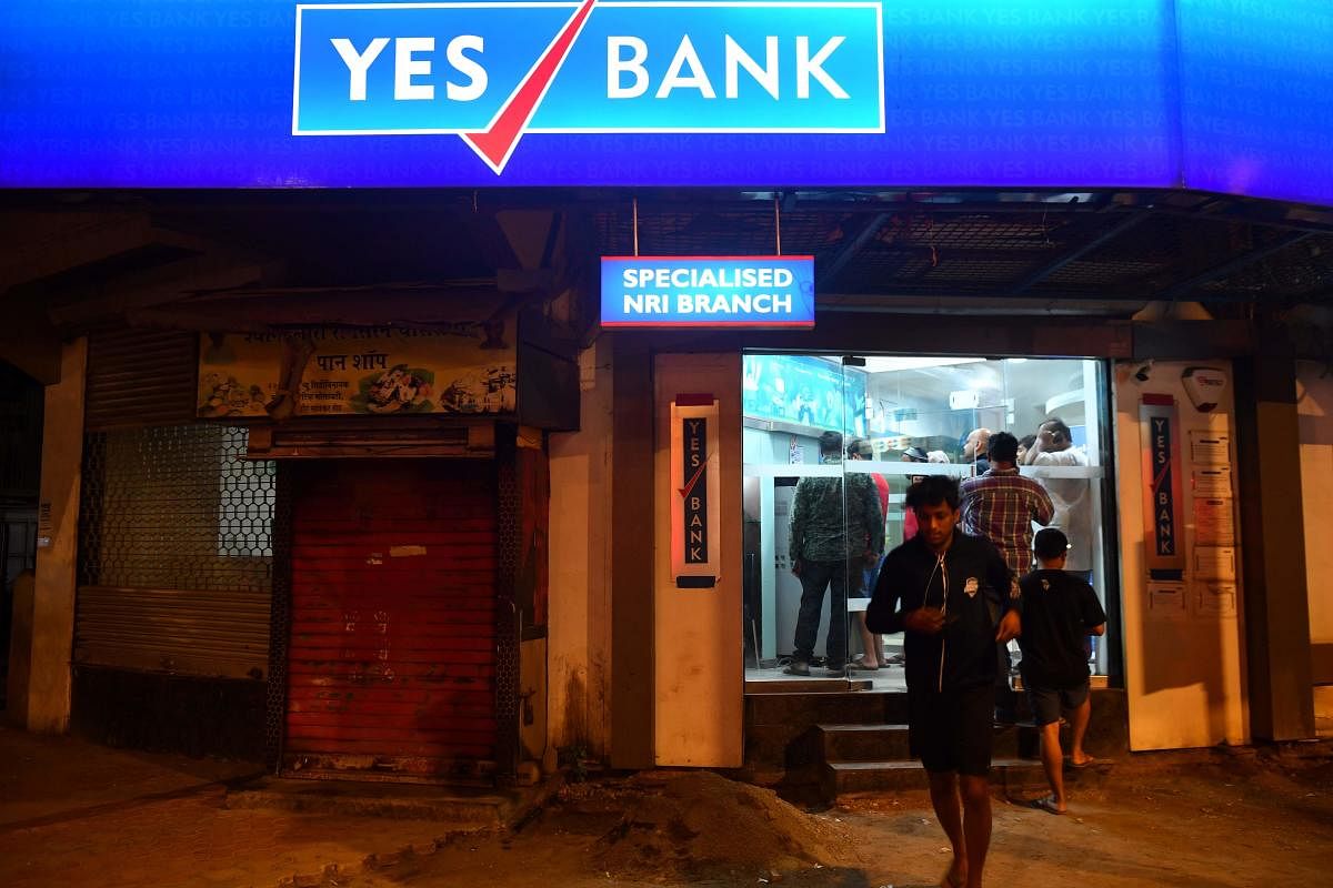 Customers stand at a Yes Bank ATM to withdraw money. AFP photo