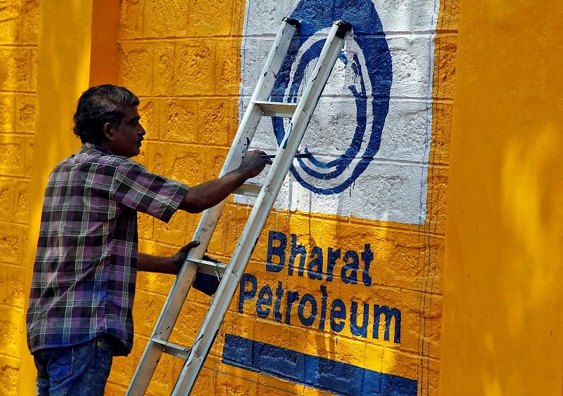 A man paints the logo of oil refiner Bharat Petroleum Corp (BPCL) on a wall on the outskirts of Kochi, India. (Reuters Photo)