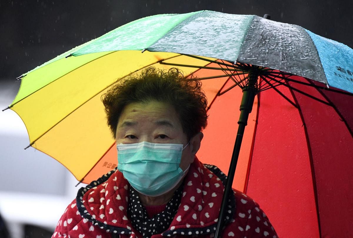 A woman wearing a face mask walks with an umbrella along a street in Jiujiang in China's central Jiangxi province on March 6, 2020. Credit: AFP Photo