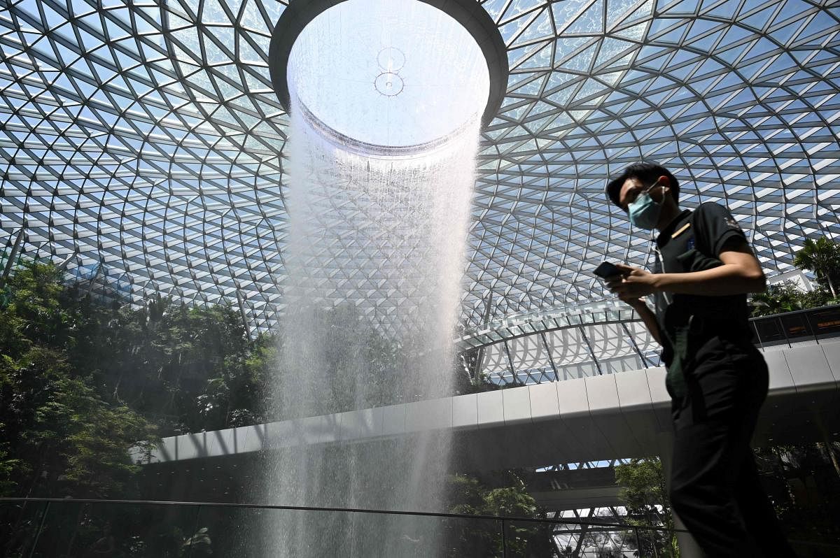 A man, wearing a protective facemask amid fears about the spread of the COVID-19 novel coronavirus, walks past the Rain Vortex display at Jewel Changi Airport in Singapore. AFP