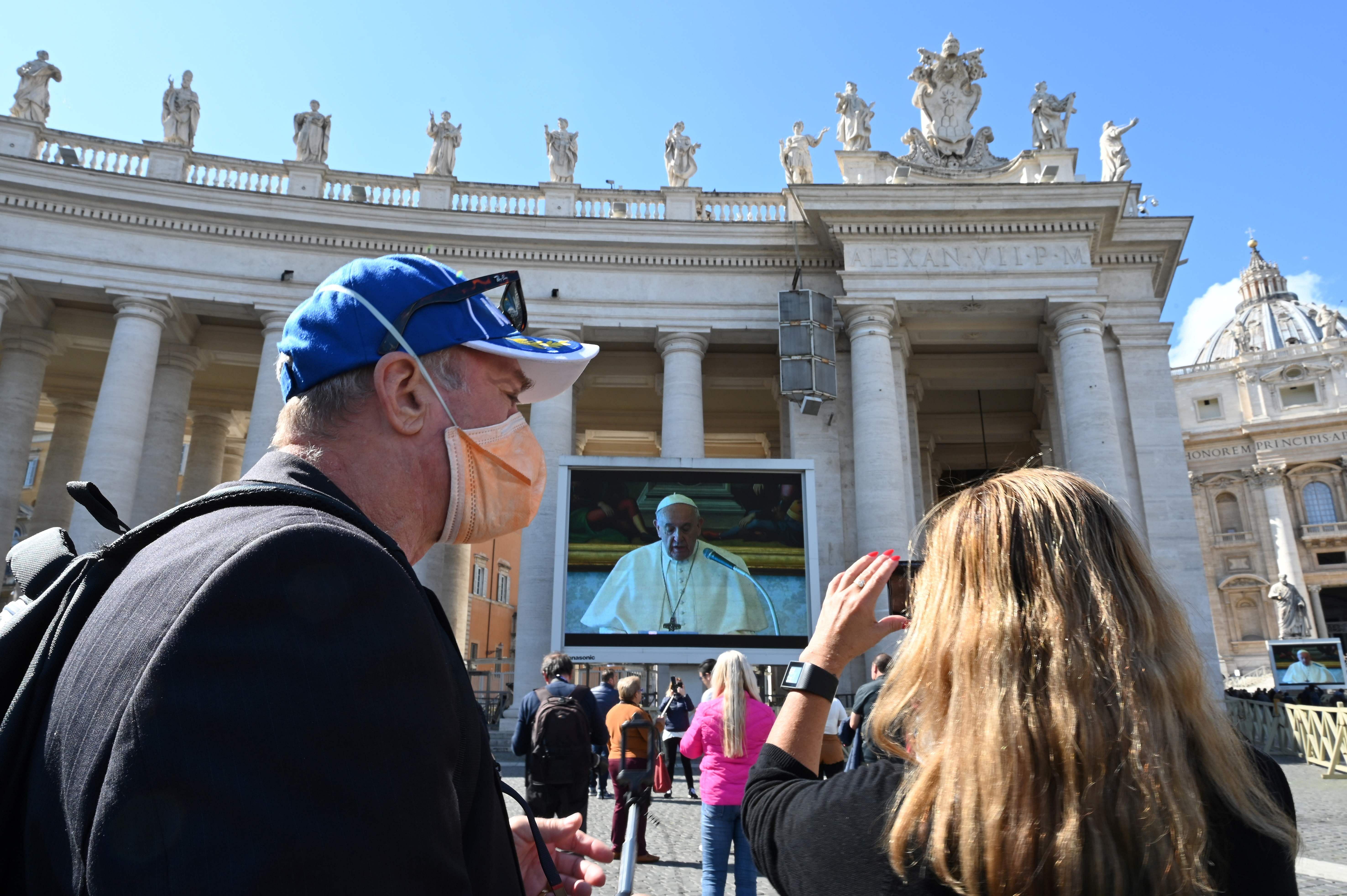  A couple takes smartphone pictures of a screen live-broadcasting Pope Francis' Sunday Angelus prayer on St. Peter's Square at the Vatican (Credit: AFP Photo)
