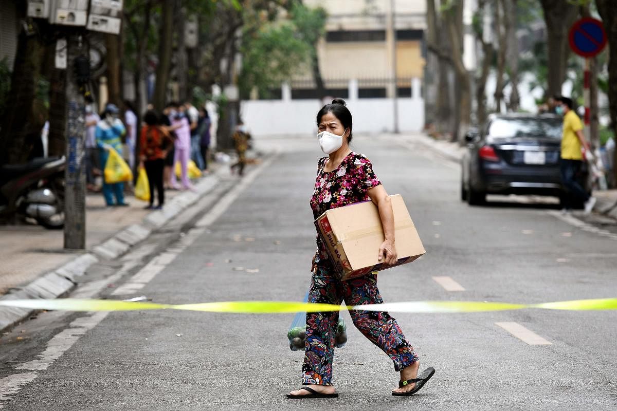 A woman wearing a facemask amid concerns of the spread of the COVID-19 coronavirus walks inside an isolated area on Truc Bach street in Hanoi on March 8, 2020. (AFP Photo)