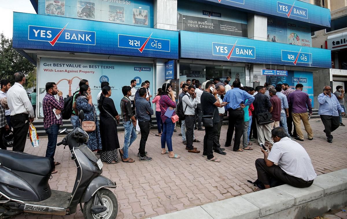 People wait outside a Yes Bank branch to withdraw their money in Ahmedabad. Credit: Reuters File Photo