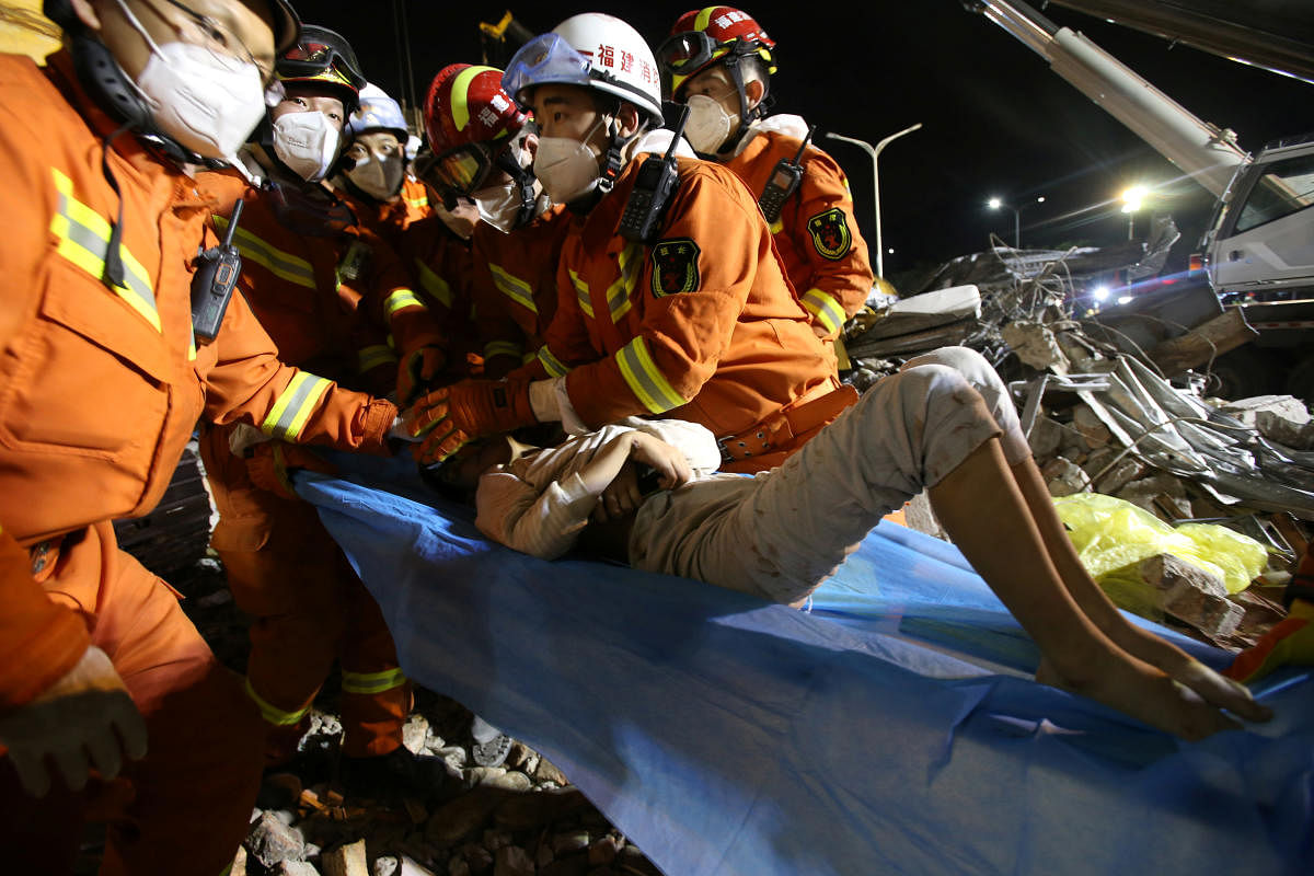 Rescue workers wearing face masks move a boy from the rubble of a collapsed hotel which has been used for medical observation following an outbreak of the novel coronavirus, in the southeast Chinese port city of Quanzhou, Fujian. Reuters