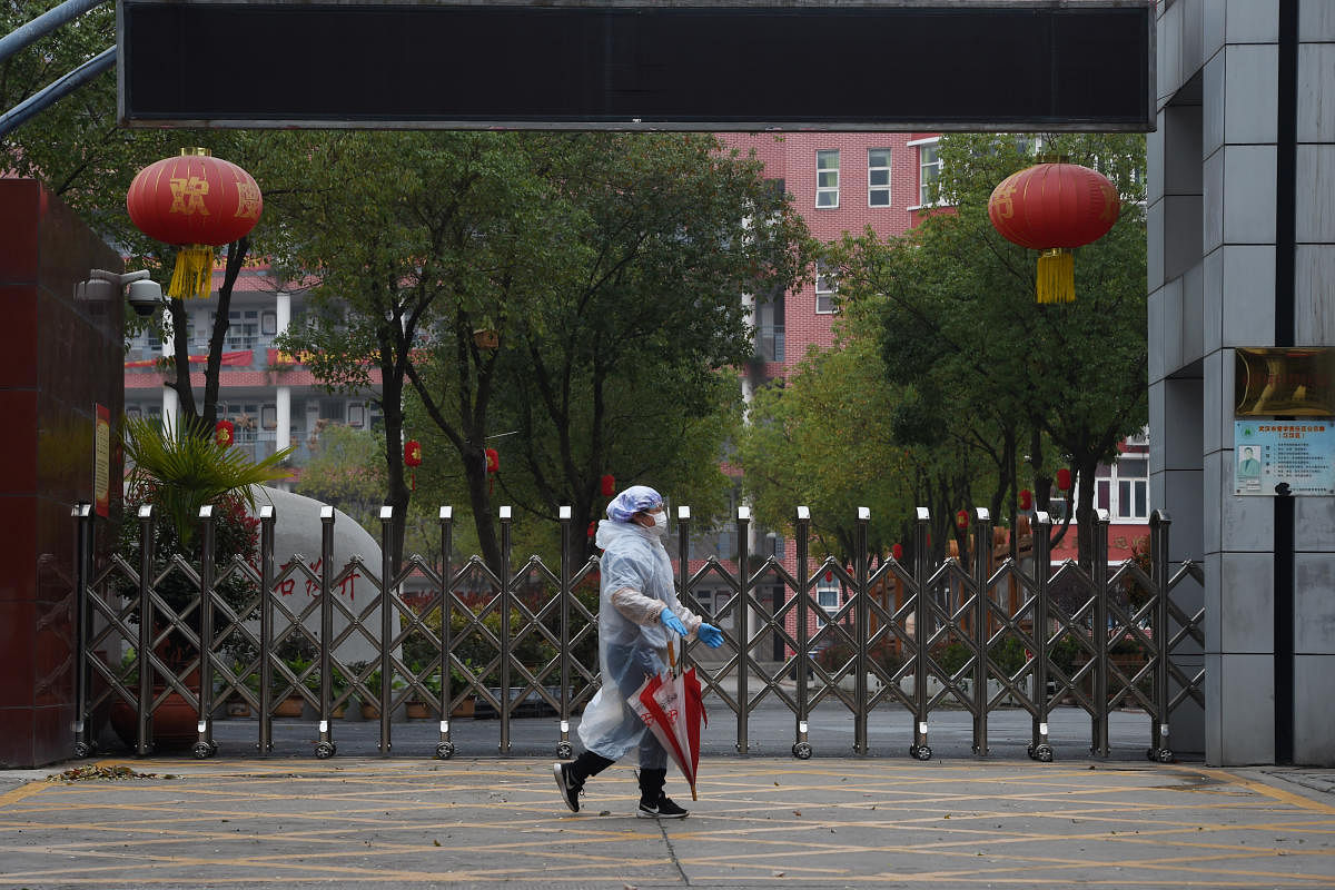Resident in protective gear walks past the entrance of a closed secondary school in Wuhan, the epicentre of the novel coronavirus outbreak. Credit: Reuters Photo