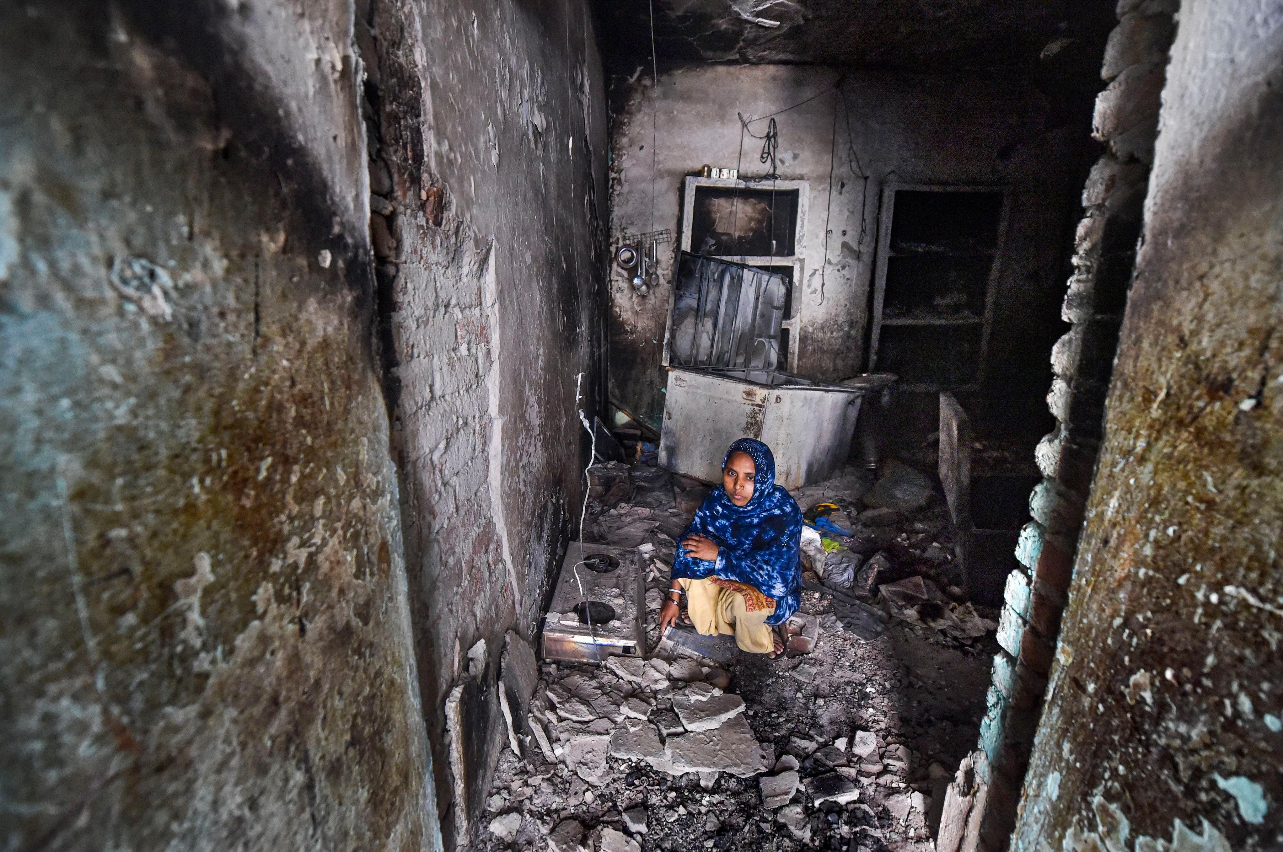  A woman sits in her house, burnt in recent violence over the amended citizenship law, in Khajuri Khas Extension of Northeast Delhi. (Credit: PTI)
