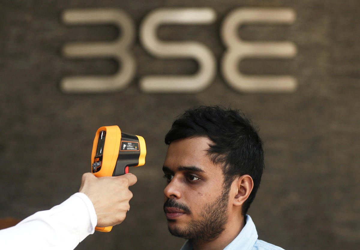 A security official scans a visitor with an infrared thermometer to check his temperature as a precautionary measure against coronavirus outside the Bombay Stock Exchange (BSE) in Mumbai. (REUTERS Photo)