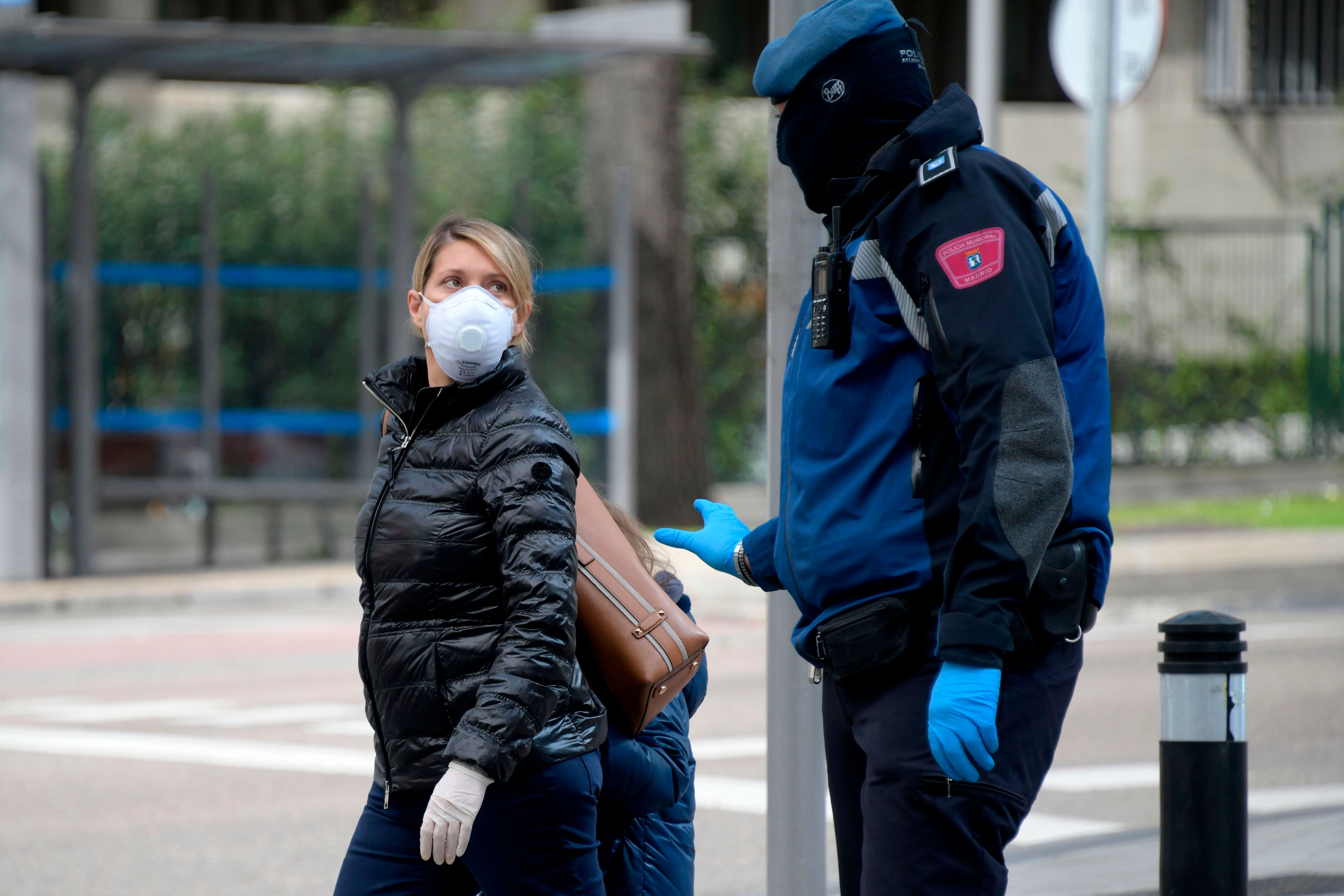 A policeman talks to a woman wearing a face mask in Madrid on March 19, 2020. - Spain announced deaths due to the novel coronavirus had risen about 30 percent over the past 24 hours to 767. (AFP Photo)