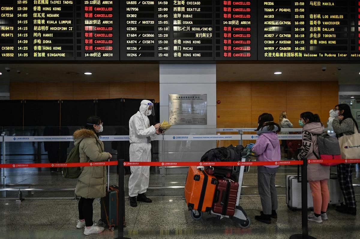 An airport security staff member wearing protective gear, amid concerns over the COVID-19 coronavirus outbreak, escorts passengers to a bus that will take them to their city, after arriving at Shanghai Pudong International Airport in Shanghai in March 19, 2020. Credit: AFP Photo