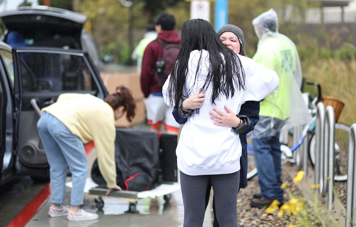 Students hug while moving their belongings from their dormitories at San Diego State University in San Diego, California, on March 18, 2020. (AFP Photo)