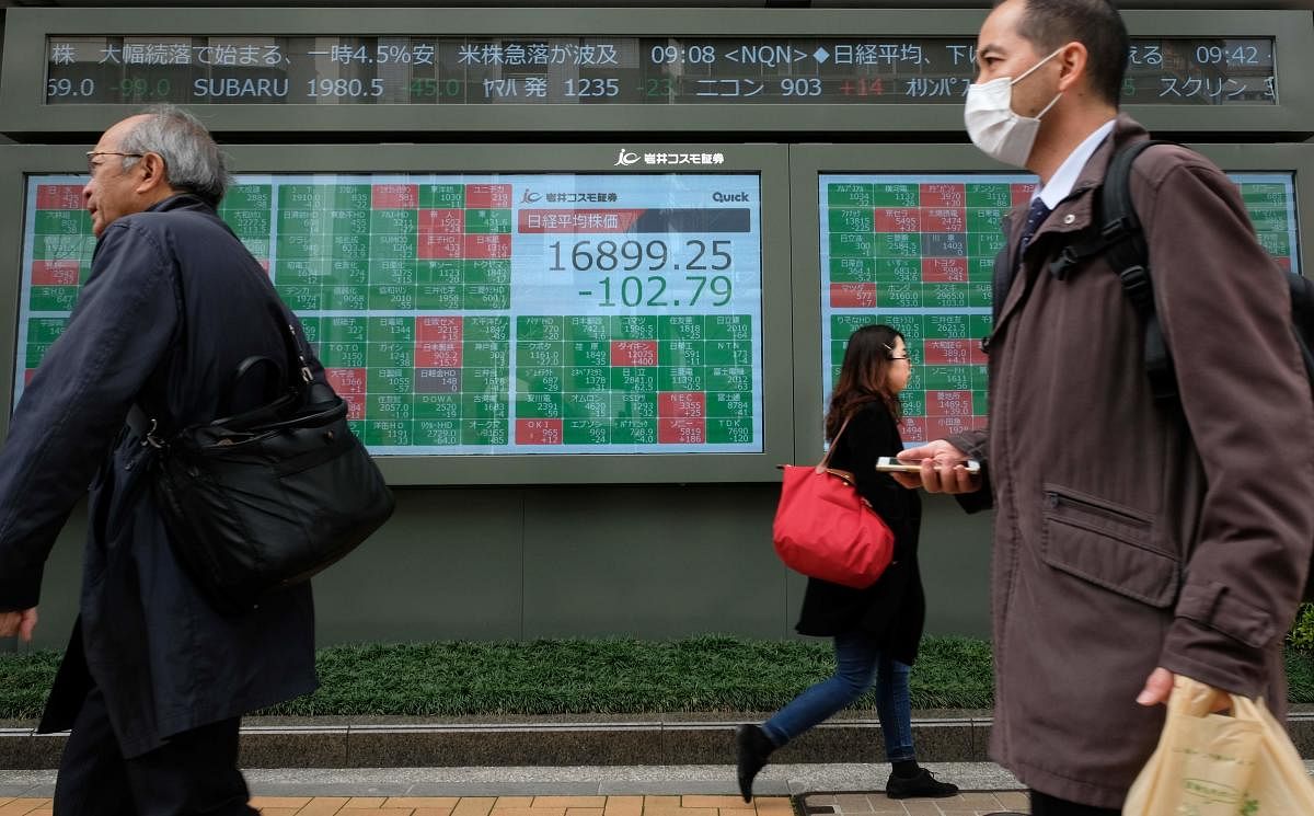 Pedestrians walk past a quotation board displaying share price numbers of the Tokyo Stock Exchange in Tokyo. AFP