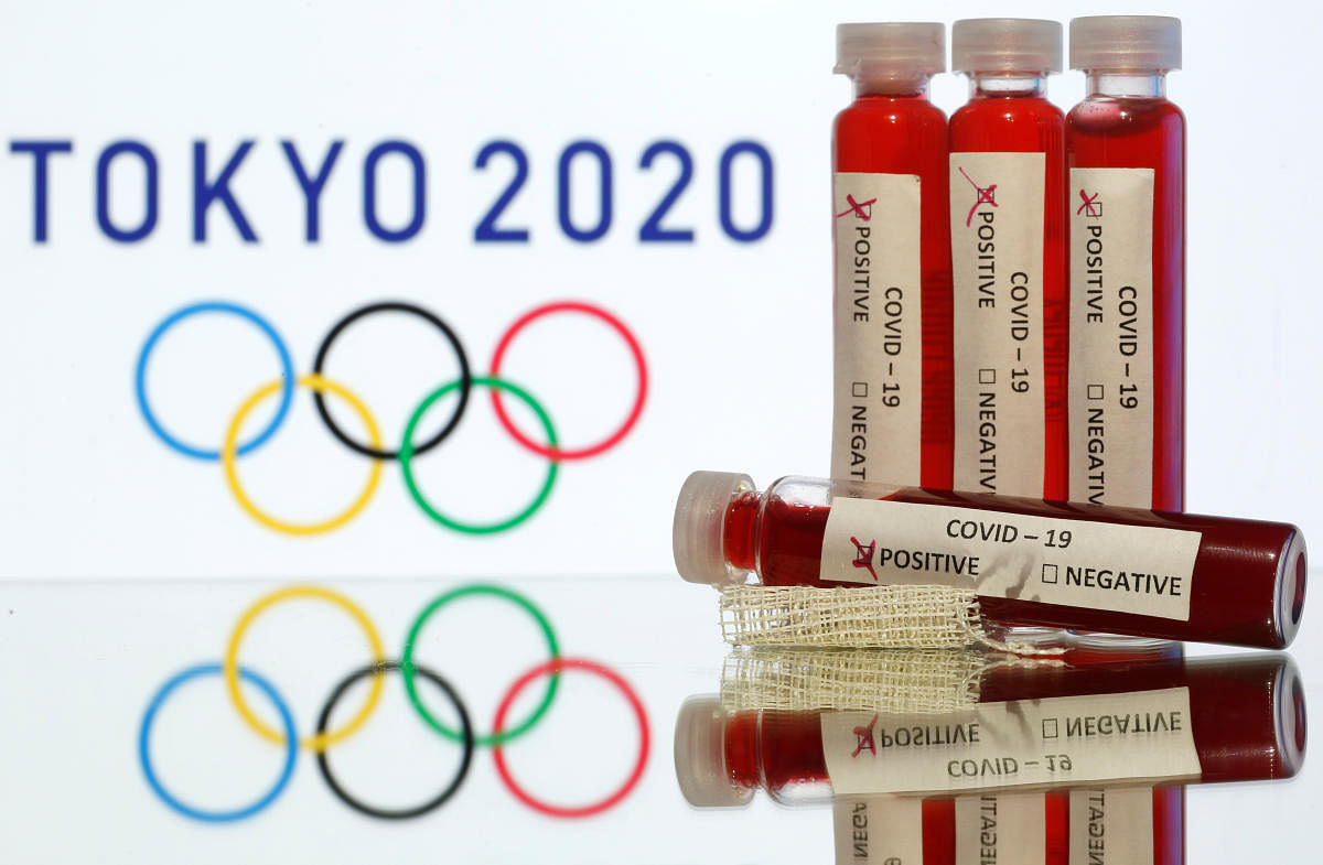 Fake blood in seen in test tubes labelled with coronavirus disease (COVID-19) in front of a displayed Tokyo 2020 Olympics logo. Credit: Reuters Photo