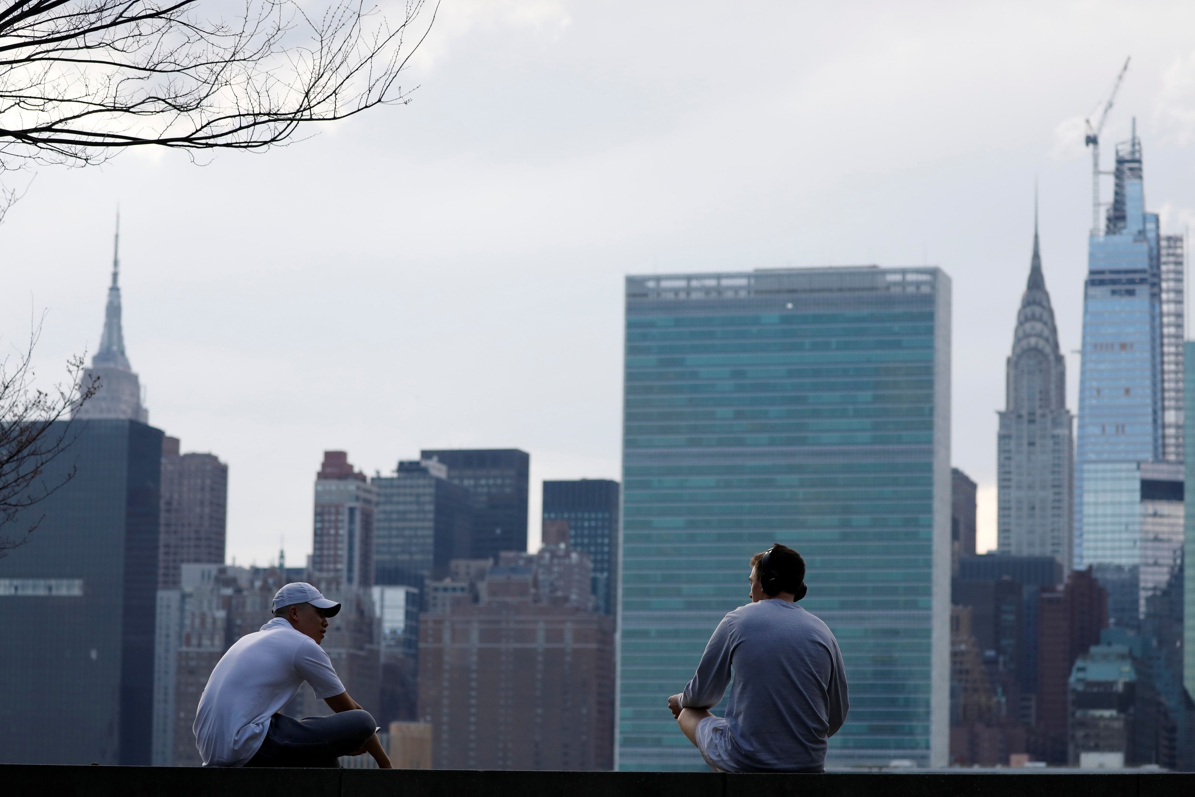 People talk to each other from a distance in front of the Manhattan skyline as the coronavirus disease (COVID-19) outbreak continues. (Credit: Reuters)