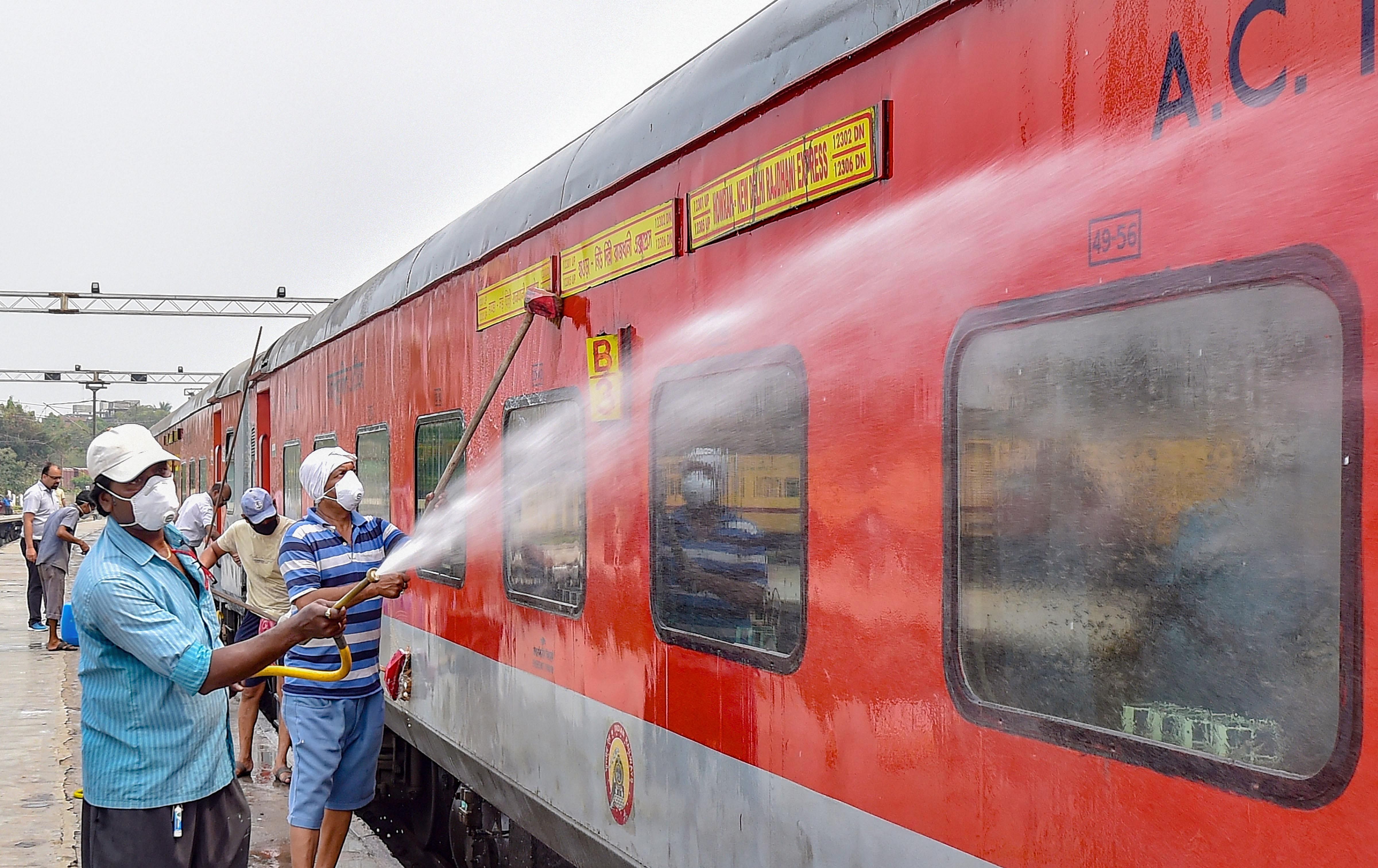 Railway workers spray disinfectant on Howrah-New Delhi Rajdhani Express. (PTI Photo)