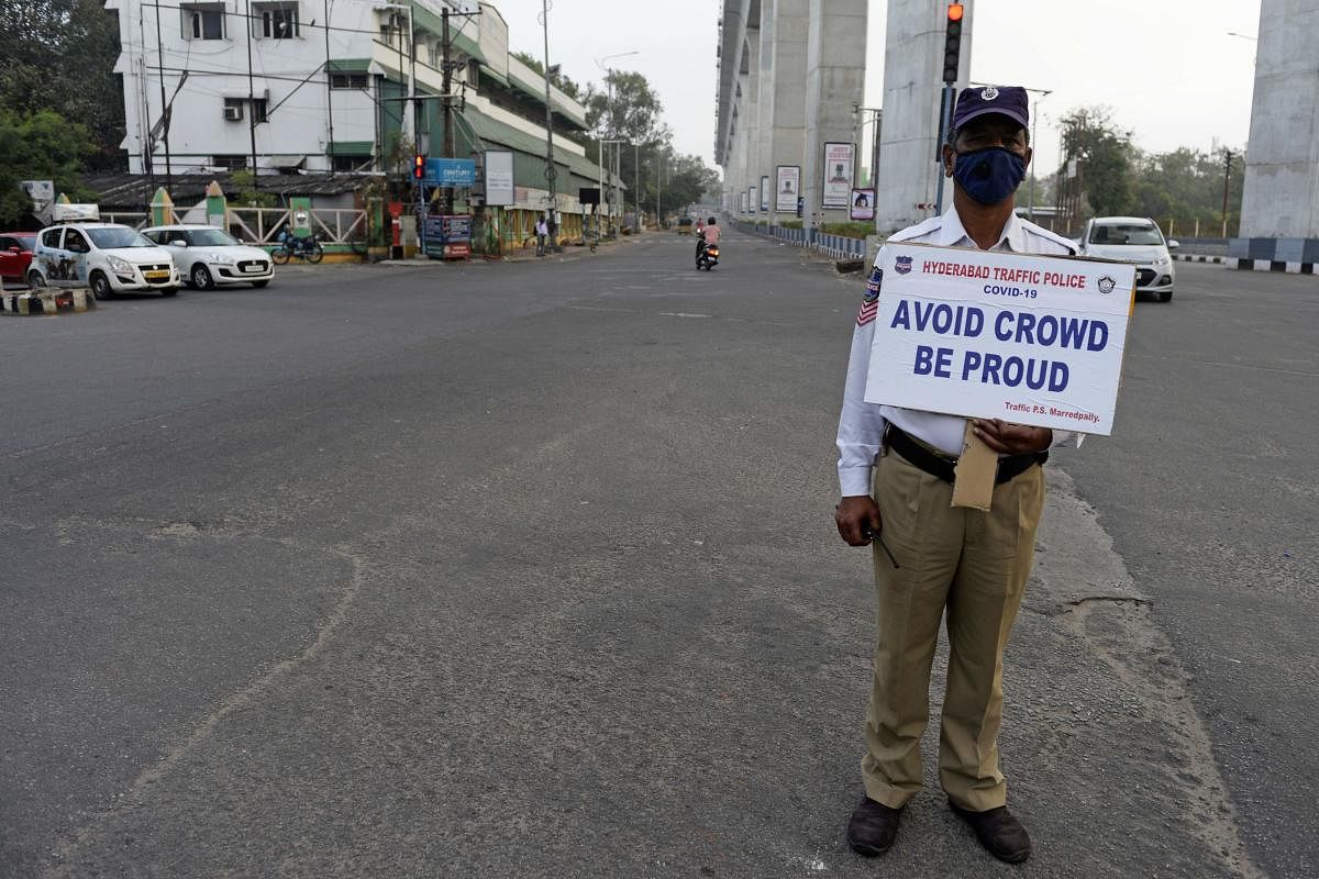 A traffic police personnel holds a placard as he stands guard on a deserted road junction during a one-day Janata (civil) curfew imposed amid concerns over the spread of the COVID-19 novel coronavirus, in Secunderabad, the twin city of Hyderabad, on March 22, 2020. Credit: AFP Photo