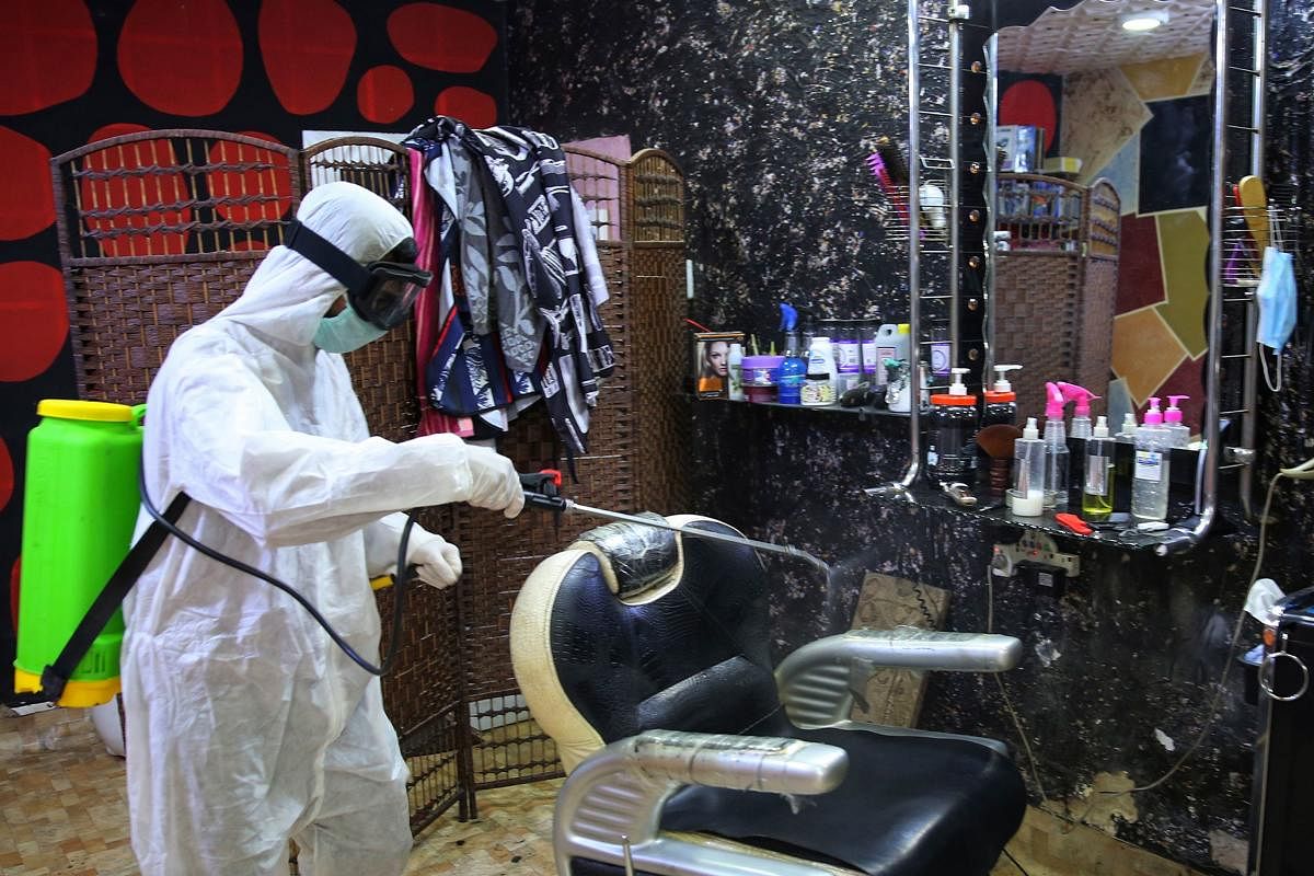 A volunteer disinfects a salon in Baghdad's Bayaa neighbourhood on March 21, 2020 as a preventive measure against the spread of the coronavirus COVID-19. (AFP Photo)