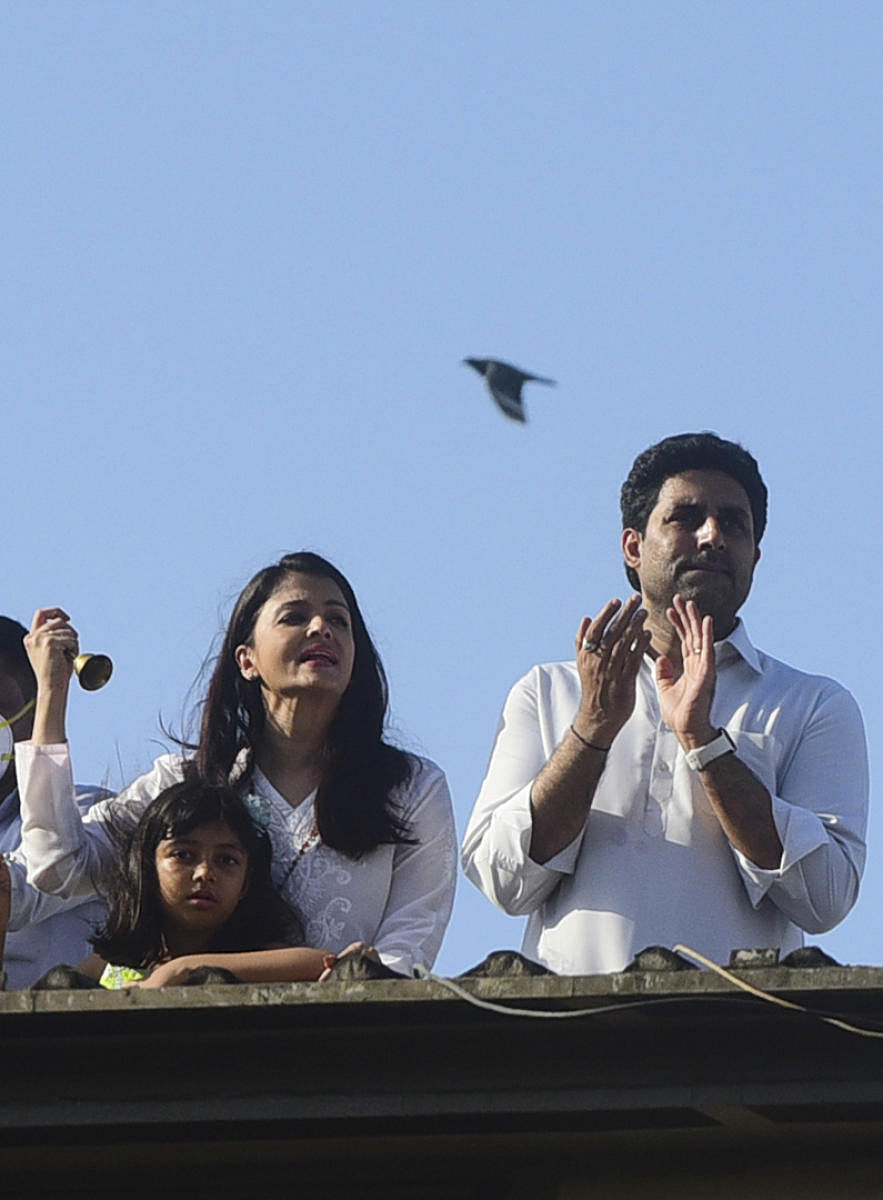 Bollywood actors Abhishek Bachchan (R) and Aishwarya Rai Bachchan along with their daughter Aaradhya clap from atop a residential building to thank essential service providers during a one-day Janata (civil) curfew imposed amid concerns over the spread of the COVID-19 (AFP Photo)