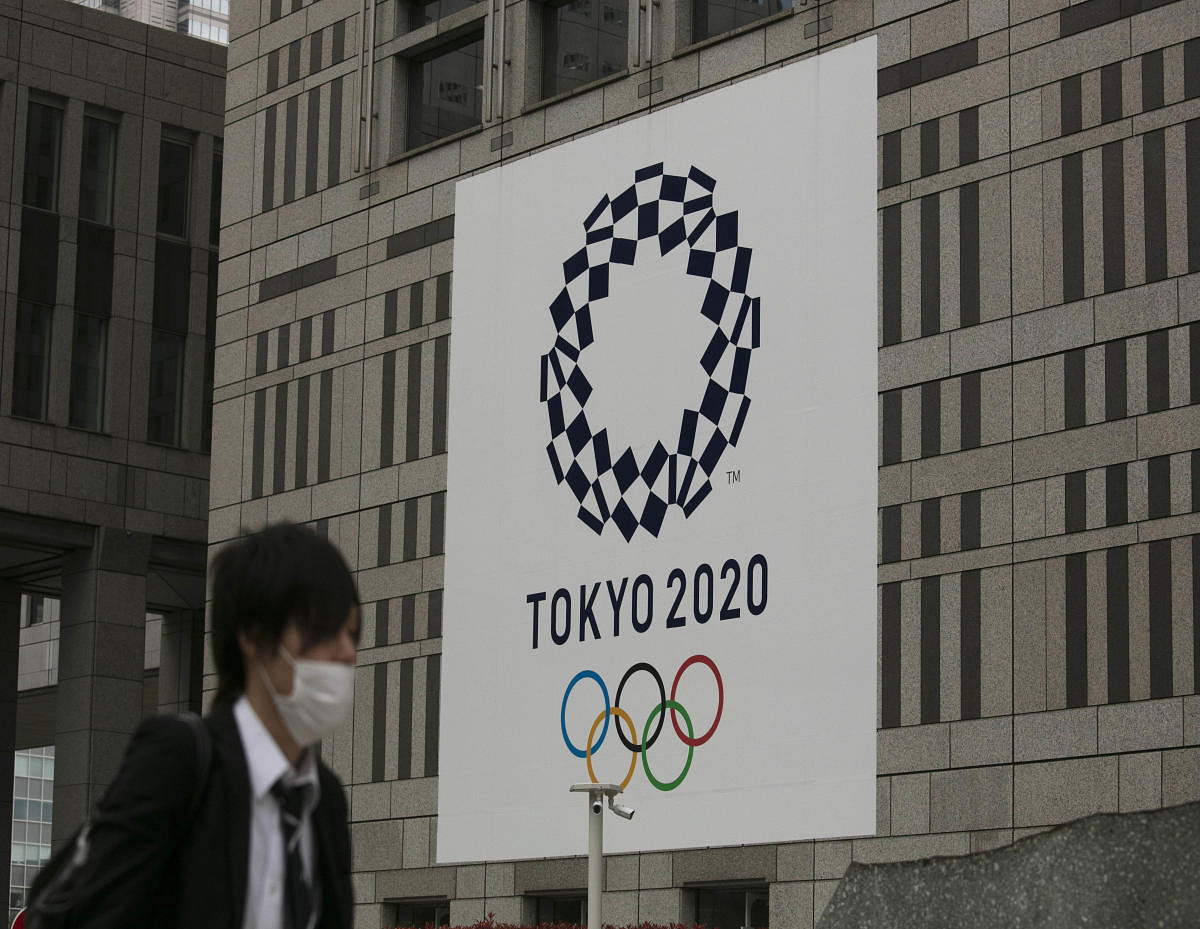 A man walks past a large banner promoting the Tokyo 2020 Olympics in Tokyo, Monday, March 23, 2020.