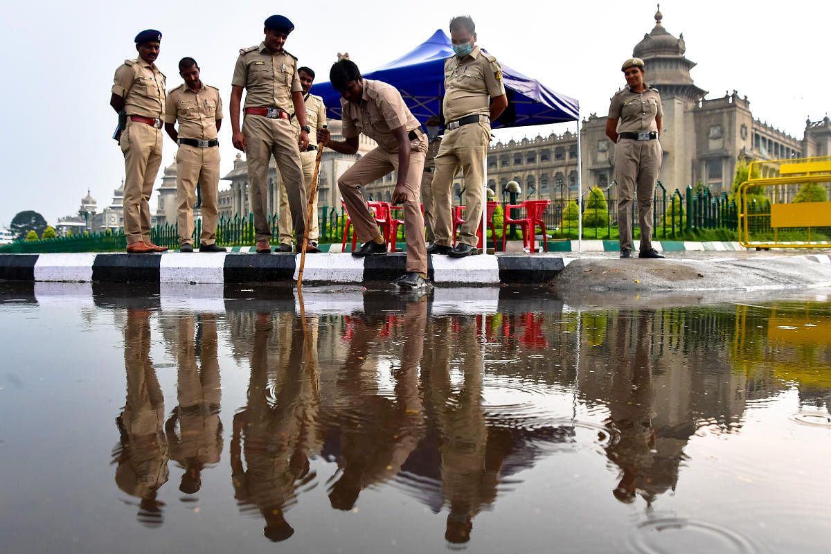 Police personnel clear stagnant water in front of the Vidhana Soudha on Monday evening. DH photo/KRISHNAKUMAR P S