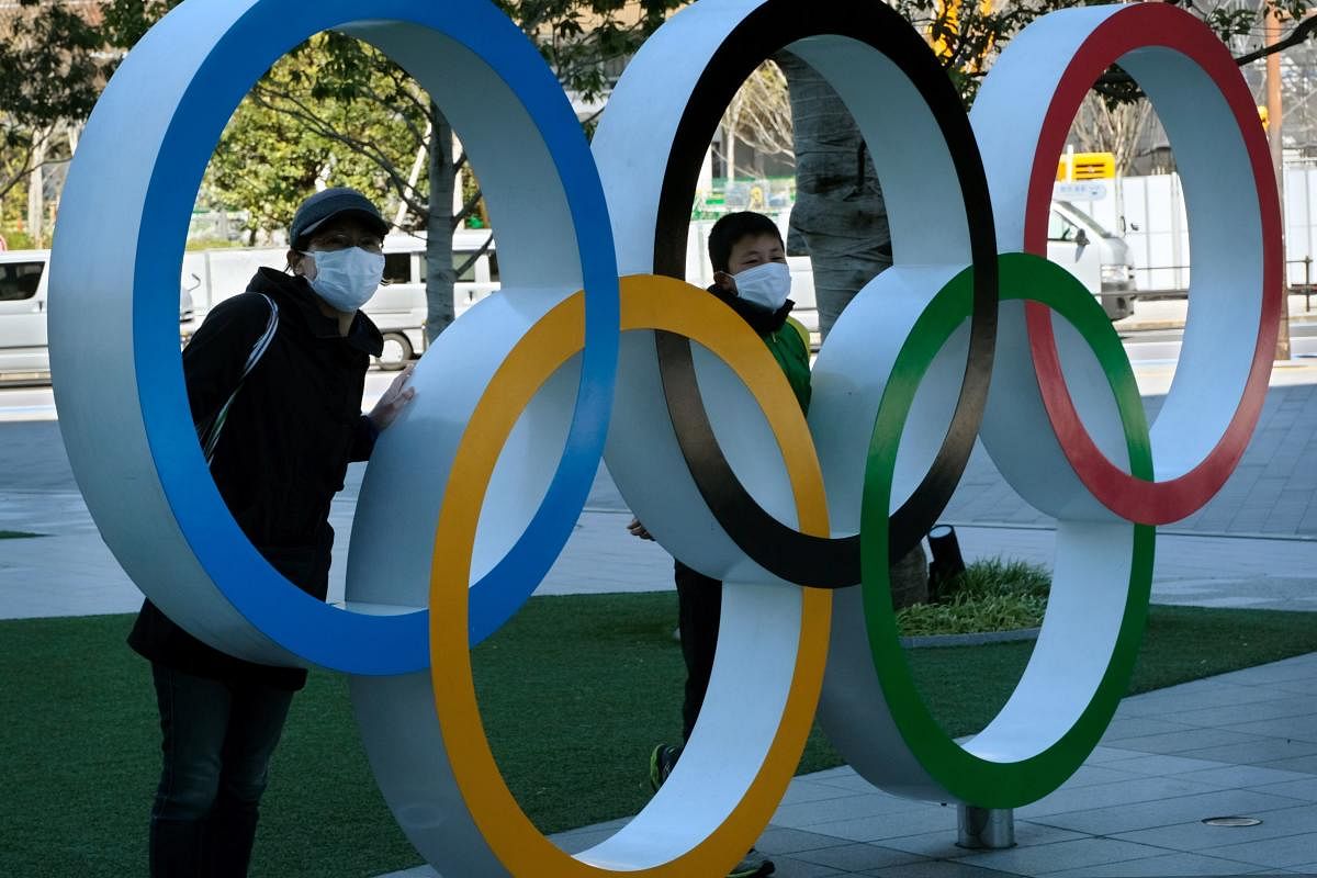Pedestrians pose with an installation of the Olympic rings in Tokyo. AFP