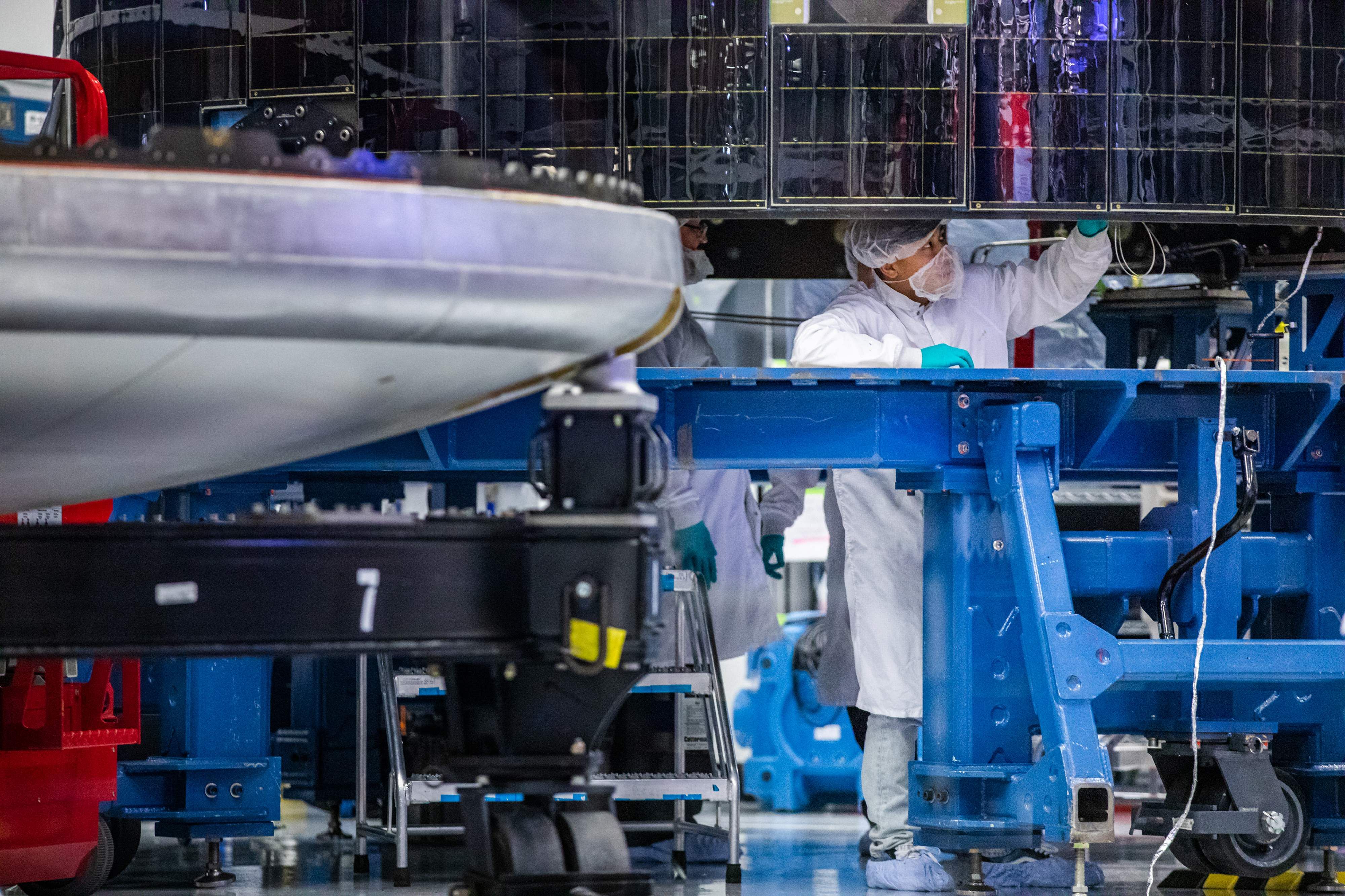 An employee of SpaceX works on the Crew Dragon reusable spacecraft during a press conference at SpaceX headquarters in Hawthorne. (Credit: AFP)