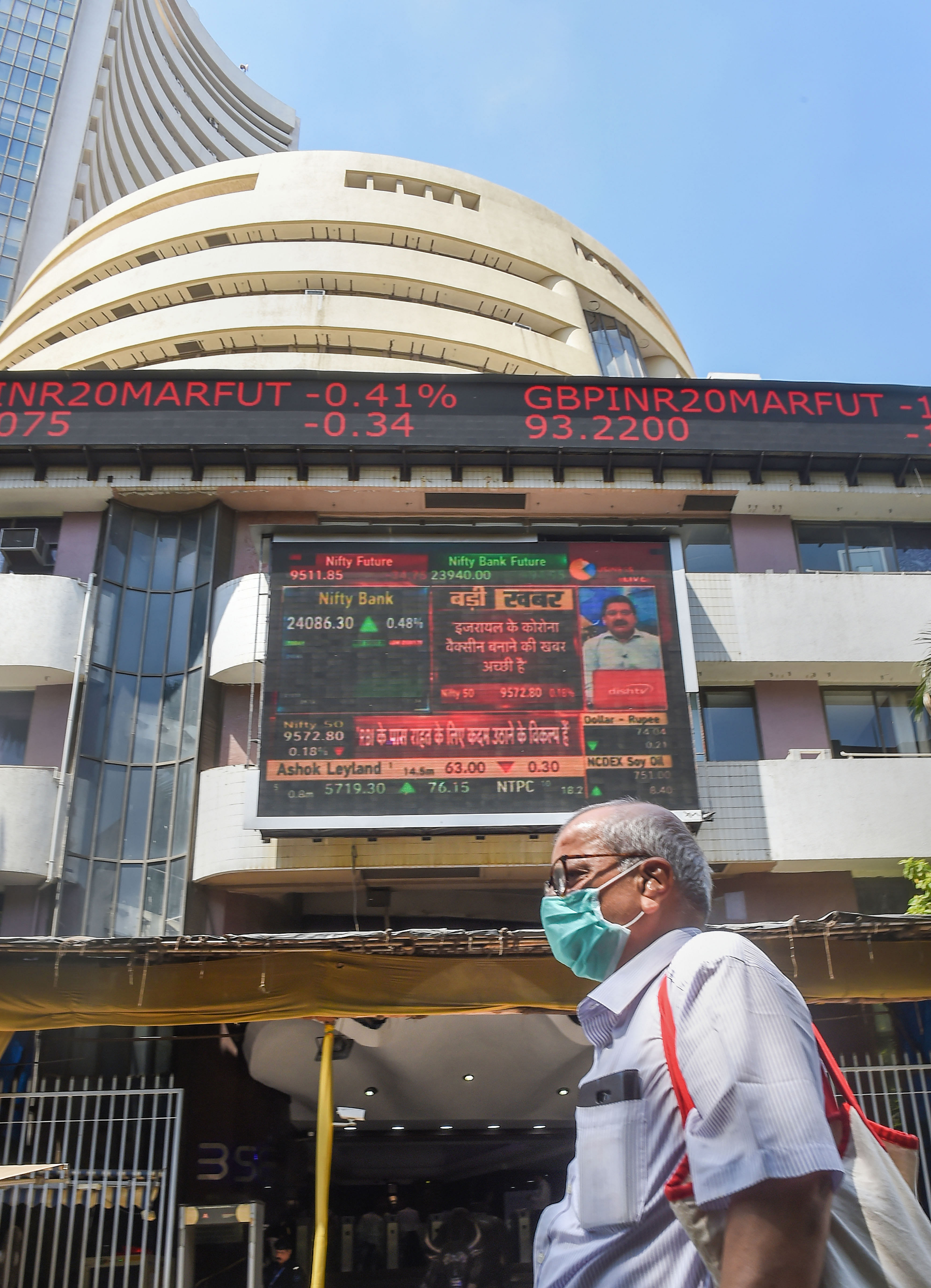  A man wears a mask and walks past the BSE building, as the Sensex crashed by nearly 3000 points, in Mumbai. (PTI Photo)