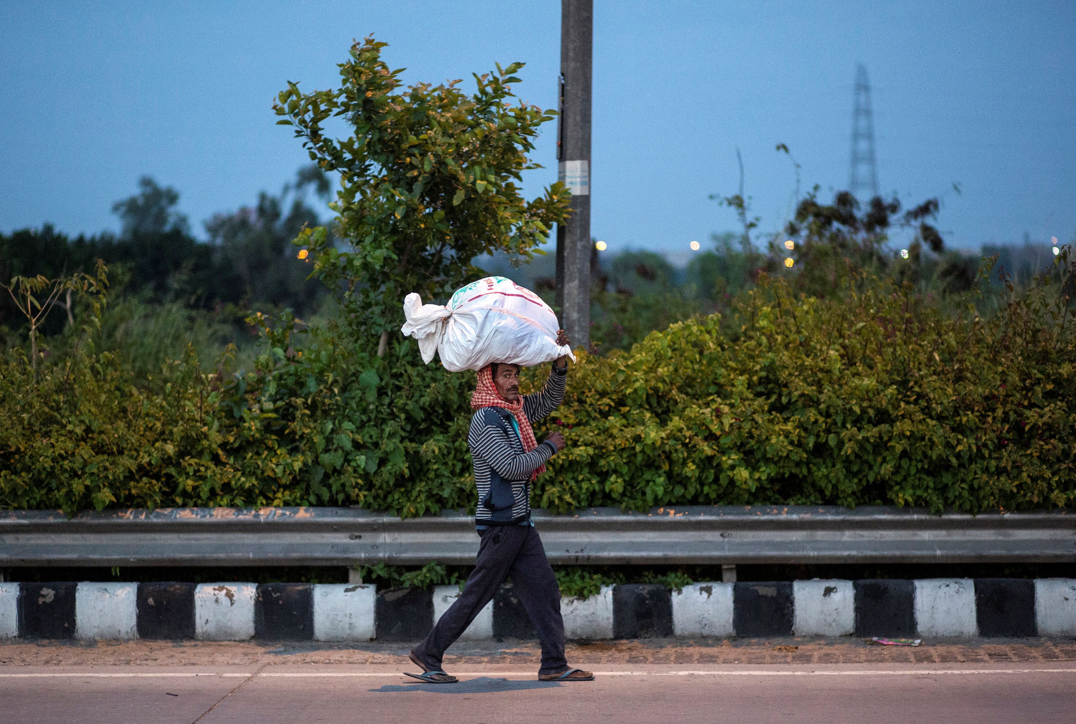 A migrant worker carries his belongings as he walks along a road to return to his village. (Credit: Reuters)