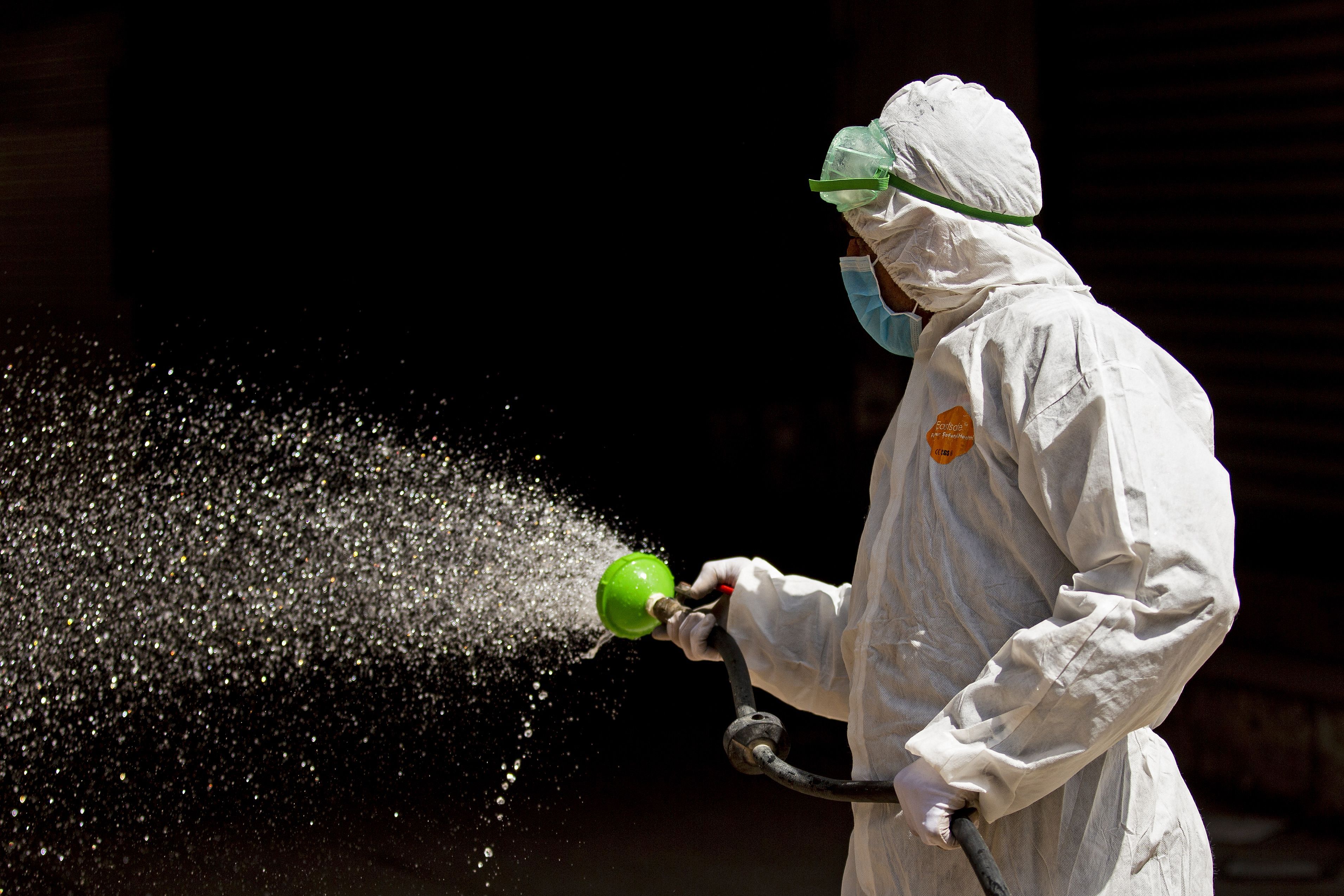 An Iraqi health worker sprays disinfecting liquid in the streets of the centre of the southern city of Basra. (Credit: AFP)