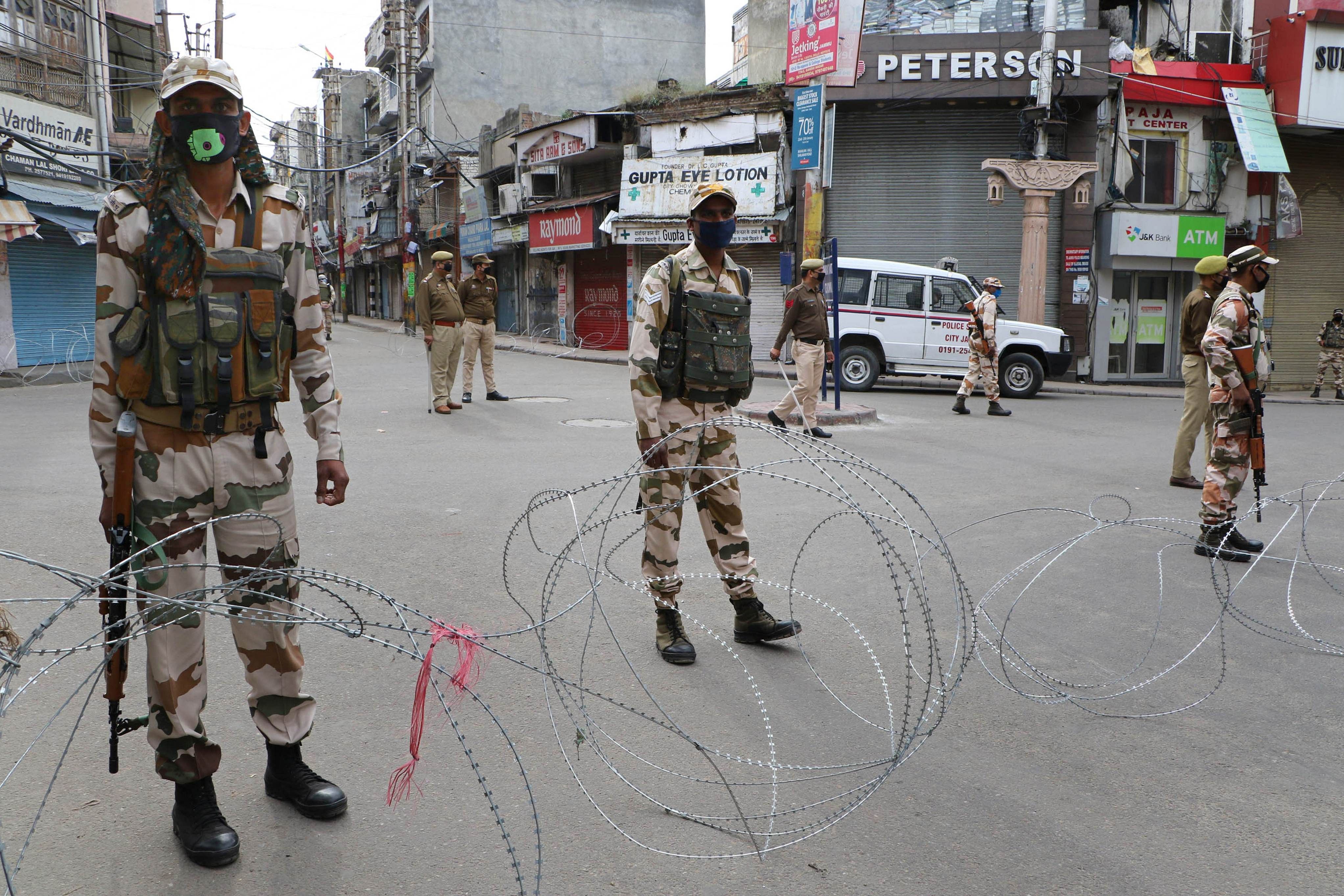 Security personnel stand guard in a street during the complete lockdown in Jammu. (Credit: PTI)