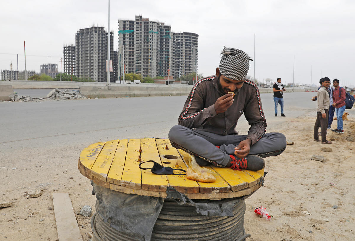 A migrant worker eats food offered by local residents on a highway as he and others are returning to their villages, after India ordered a 21-day nationwide lockdown to limit the spreading of coronavirus disease, in Ghaziabad, on the outskirts of New Delh