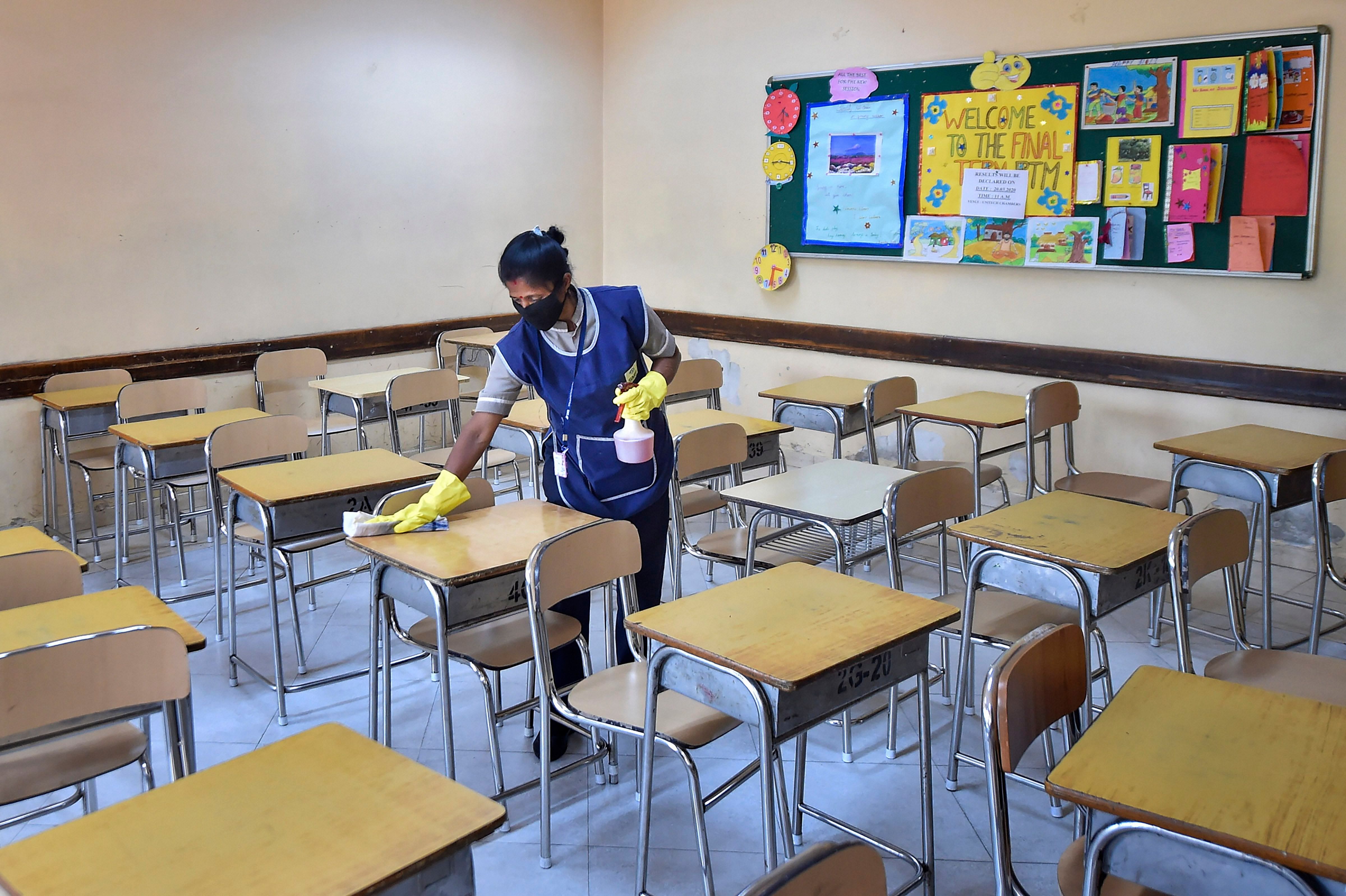A worker disinfects a classroom in the wake of novel coronavirus, at a school in Kolkata. (Credit: PTI)