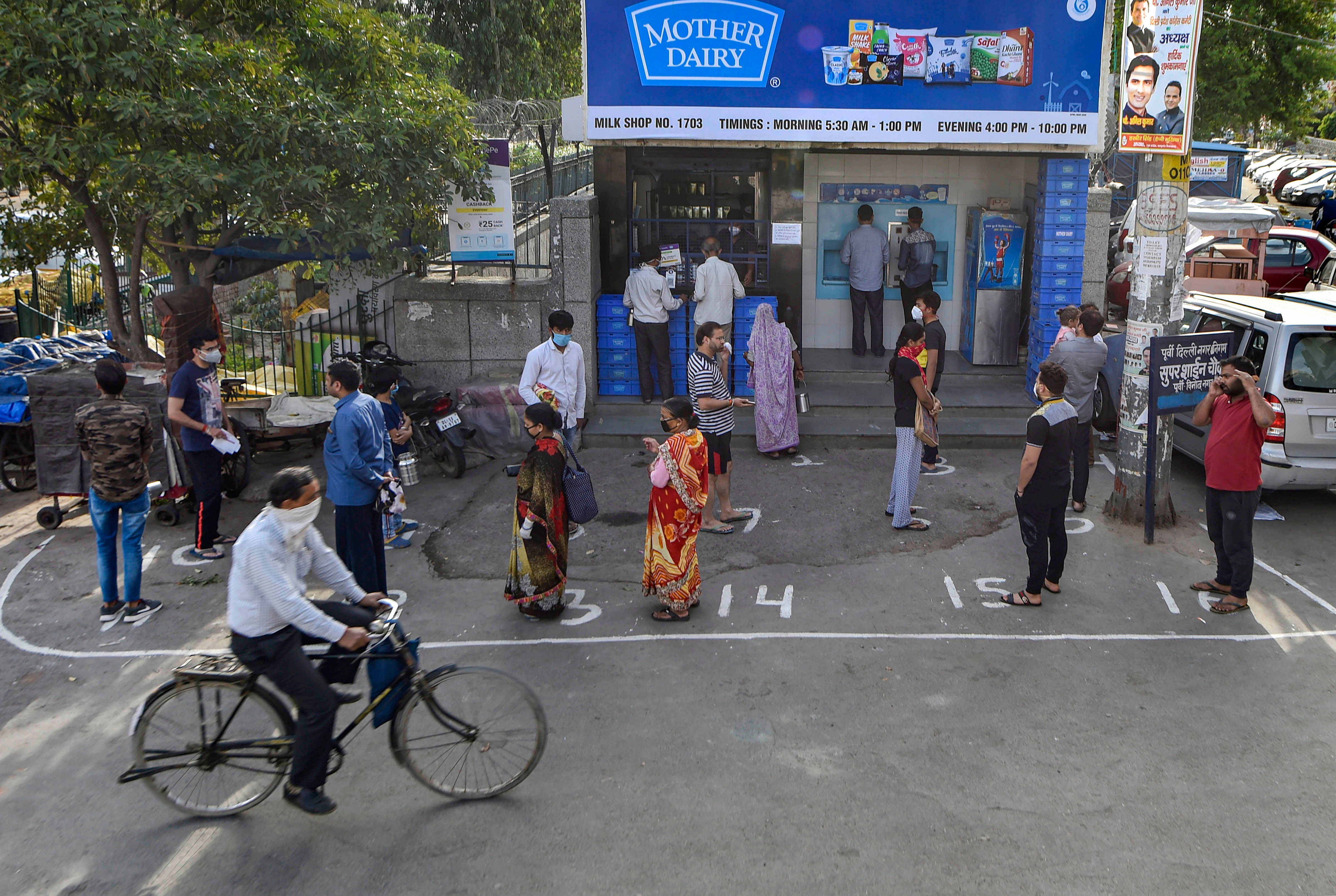 People maintain social distance as they wait outside a a mother dairy shop during a 21-day nationwide lockdown in the wake of coronavirus pandemic, at Mayur Vihar, in New Delhi. (Credit: PTI)
