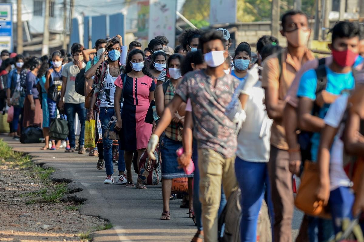 Workers carrying their belongings queue to board buses to go back to their homes in province during a government-imposed nationwide lockdown as a preventive measure against the COVID-19 coronavirus, at an industrial zone on the outskirts of Colombo on March 28, 2020. (Photo by LAKRUWAN WANNIARACHCHI / AFP)
