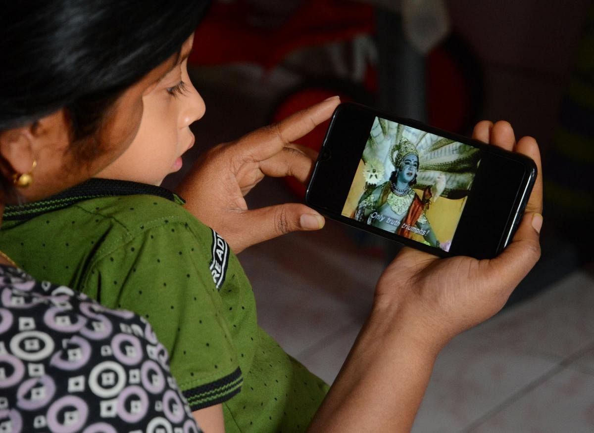 A young girl watches Ramayana in her phone, during a nationwide lockdown, imposed in the wake of coronavirus pandemic, in Guwahati. PTI