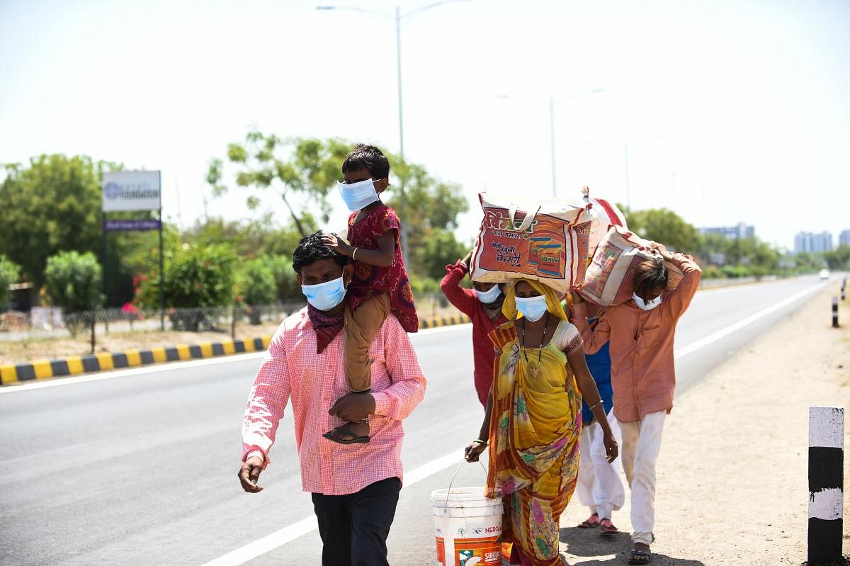 Migrant workers and their family members walk on a highway to go to their village during a government-imposed nationwide lockdown as a preventive measure against the COVID-19 coronavirus in Ahmedabad on March 28, 2020. (Photo by SAM PANTHAKY / AFP)