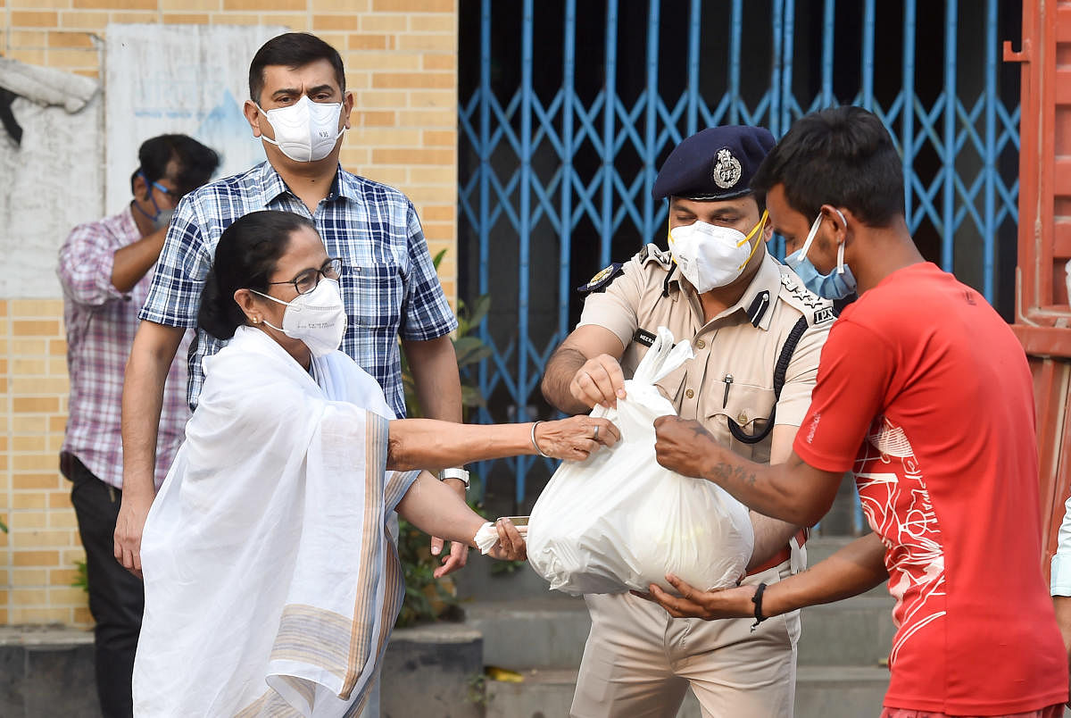 West Bengal Chief Minister Mamata Banerjee distributes relief material to rickshaw pullers during the nationwide lockdown imposed in wake of coronavirus pandemic, in Kolkata, Friday, March 27, 2020. (PTI Photo)