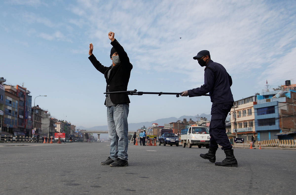 A Nepalese police officer maintains distance as he detains a man defying the lockdown imposed by the government amid concerns about the spread of coronavirus disease (COVID-19), in Kathmandu. Credit: Reuters Photo