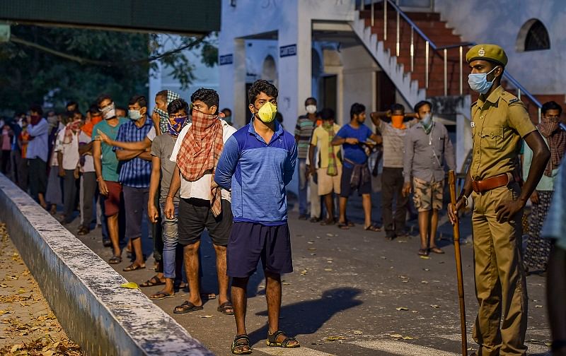 Stranded migrant workers wearing masks stand in queues to receive food distributed by volunteers at Guru Nanak College. (PTI Photo)