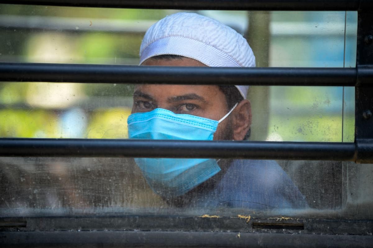 A man wearing a protective facemasks looks out while sitting on a special service bus taking them to a quarantine facility amid concerns about the spread of the COVID-19 coronavirus in Nizamuddin area of New Delhi (AFP Photo)