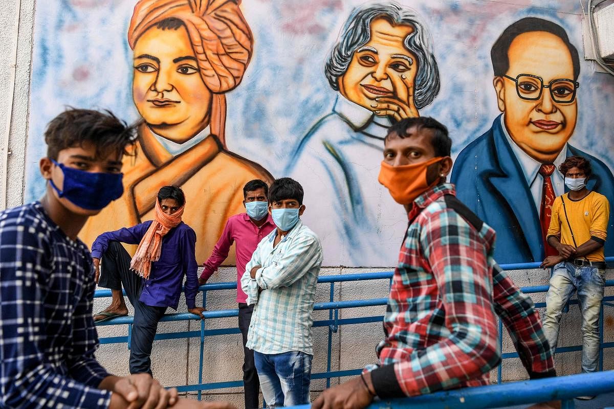 Migrant workers wait for lunch at a camp set up by Delhi Government during a government-imposed nationwide lockdown as a preventive measure against the COVID-19 coronavirus, in New Delhi on April 1, 2020. (Photo by Prakash SINGH / AFP)