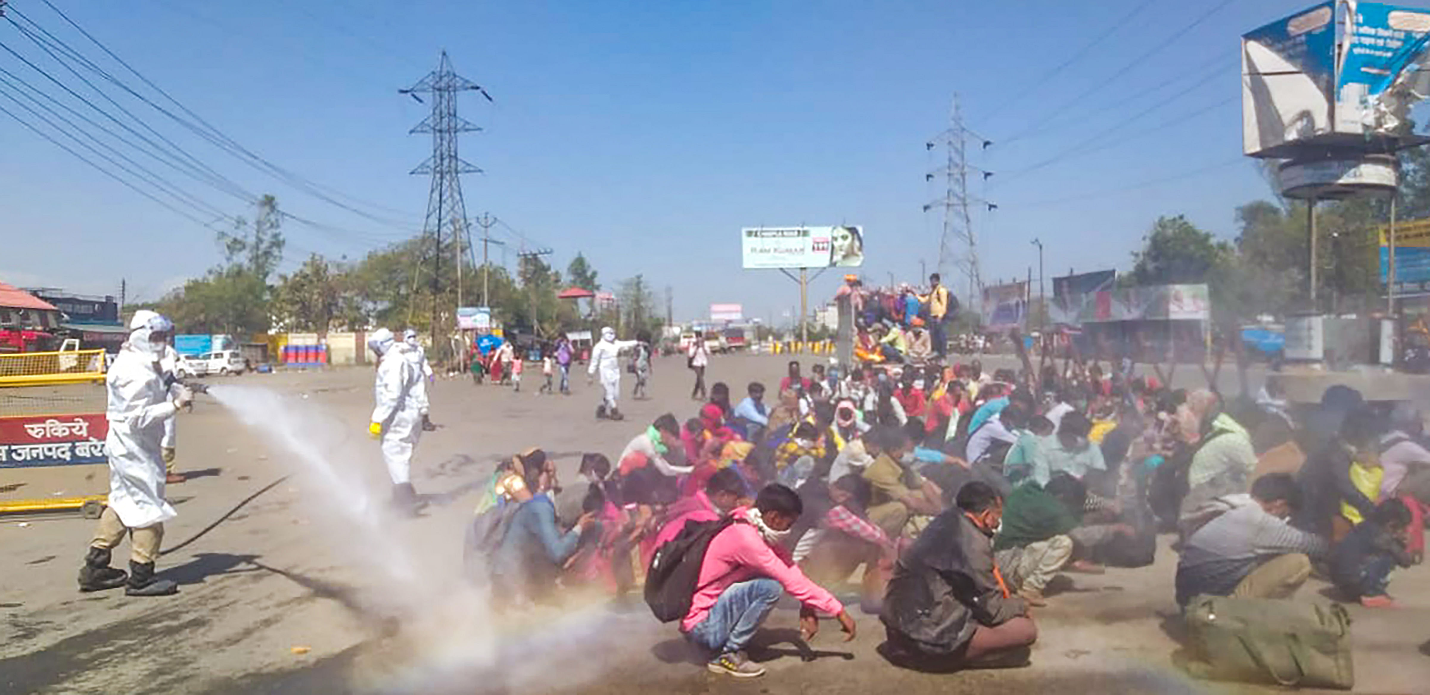 A screen grab shows healthcare workers, in protective suits, spray a solution through hose pipe on migrants before allowing them to enter the town of Bareilly, Monday, March 30, 2020. The migrants reached the town due to thenationwide complete lockdown imosed to limit the spread of coronavirus. (PTI Photo)