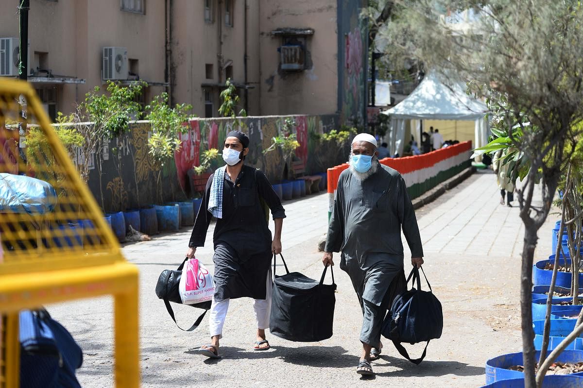 Men wearing protective facemasks walk to board a special service bus taking them to a quarantine facility amid concerns about the spread of the COVID-19 coronavirus in Nizamuddin area of New Delhi on March 31, 2020. (Photo by AFP)