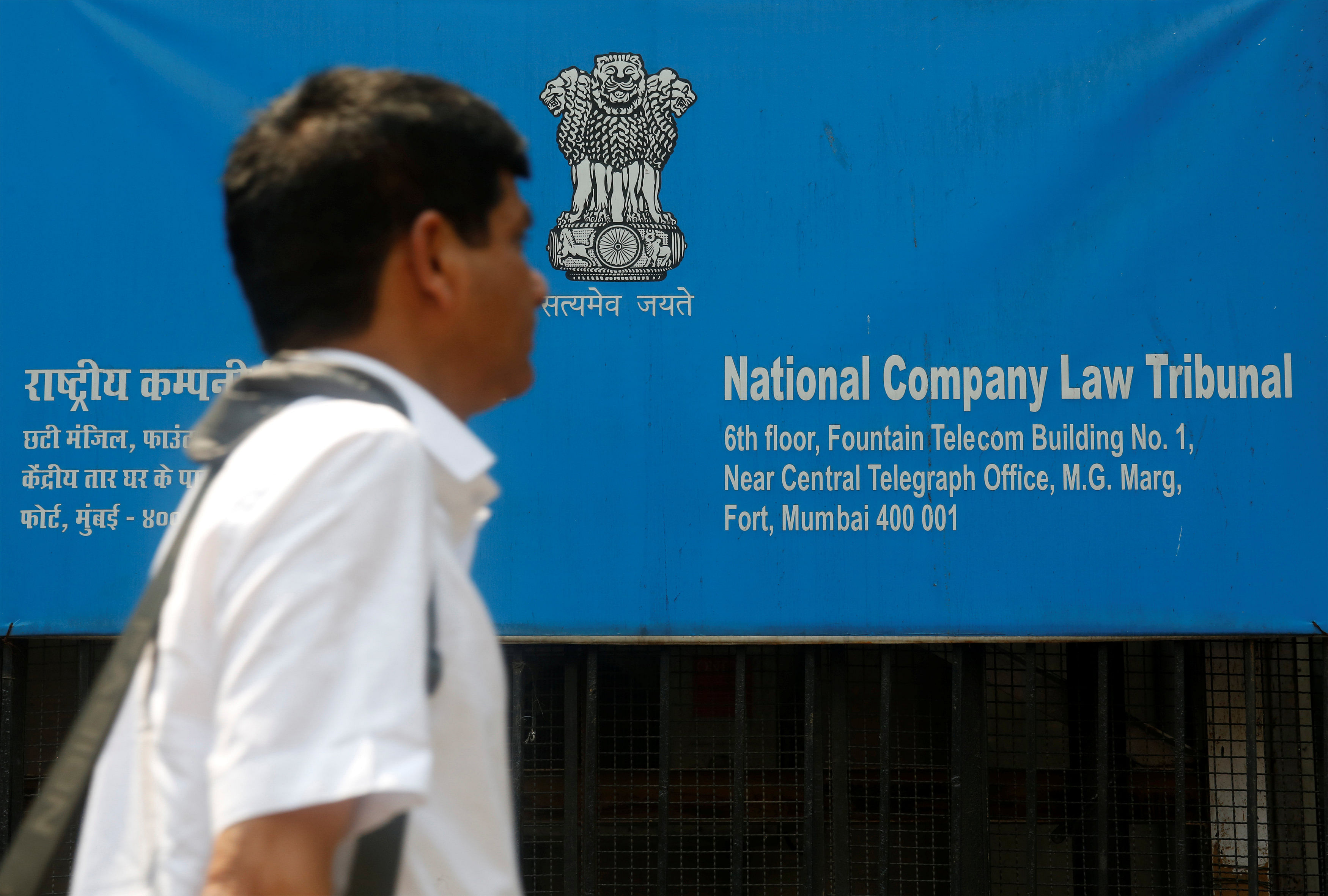 A man walks past a signboard of the National Company Law Tribunal (NCLT) outside it's office in Mumbai. (Credit: Reuters Photo)