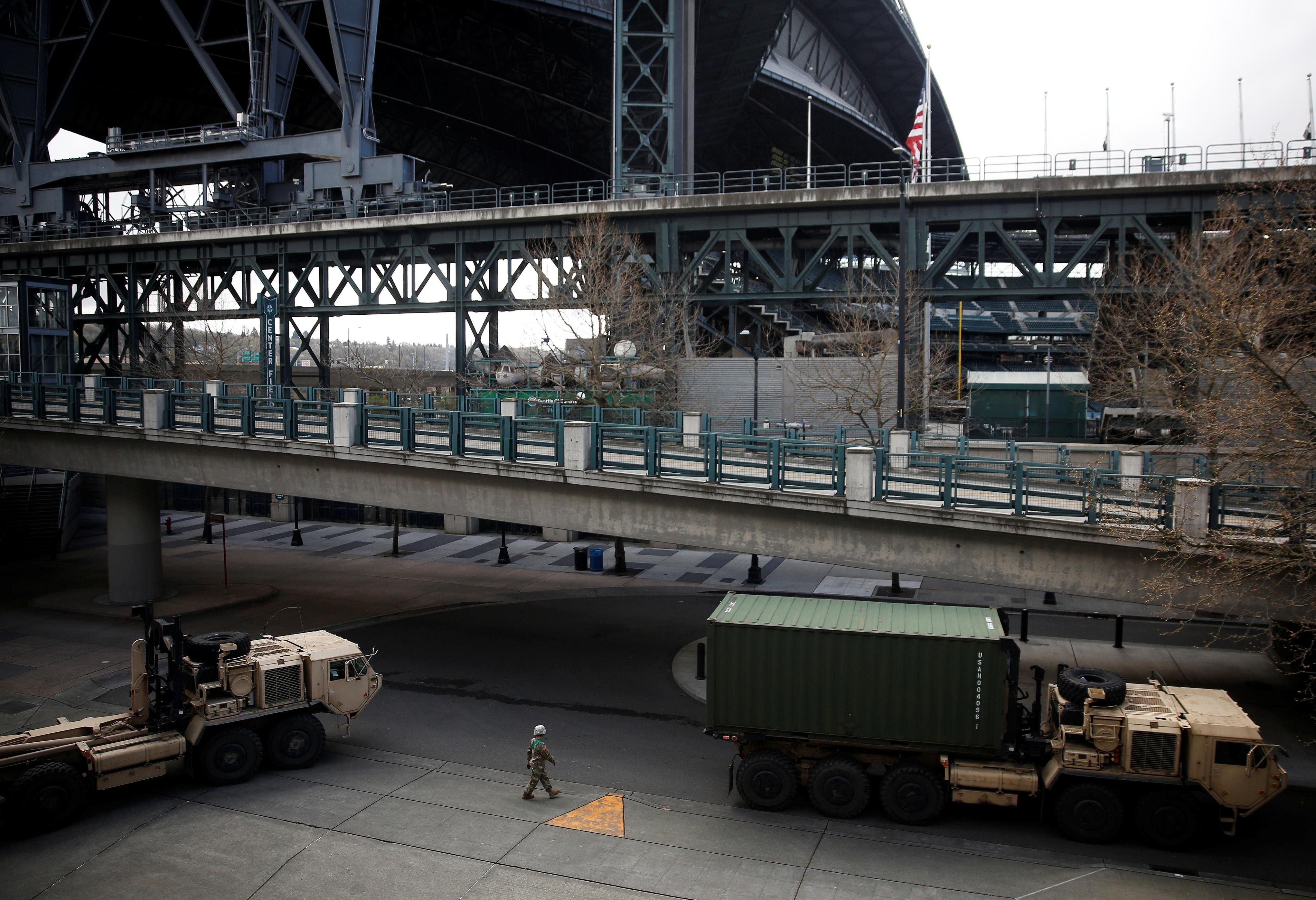 Military vehicles drive out of a field hospital for non-coronavirus patients inside CenturyLink Field Event Center, T-Mobile Park seen in the background, during the coronavirus disease (COVID-19) outbreak in Seattle, Washington. (Credit: Reuters)